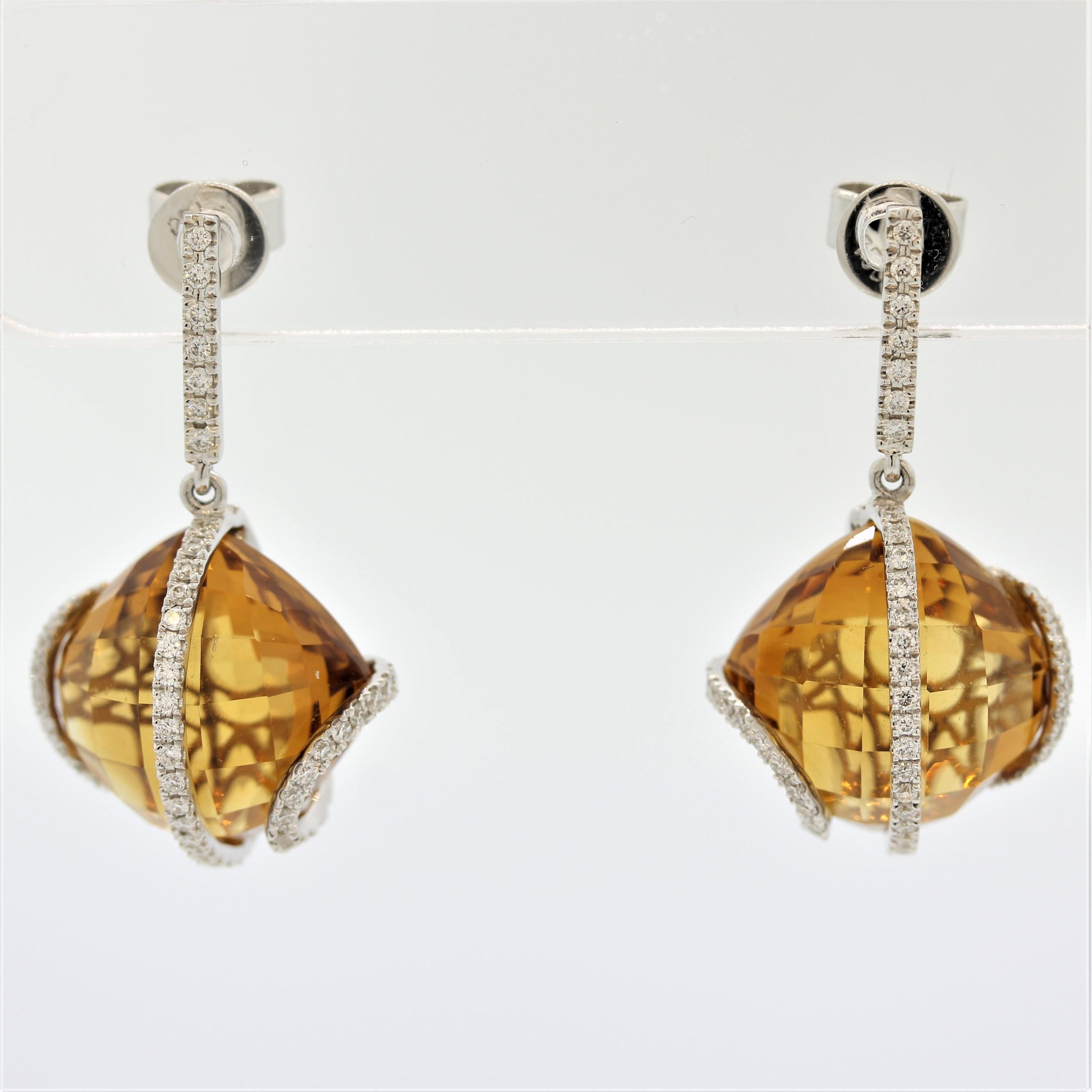 A unique and stylish pair of drop earrings. They feature 2 cushion shaped citrines weighing a total of 22.64 carats that have a bright and vibrant golden orange color. They are accented by 0.64 carats of round brilliant cut diamonds set in 18k white