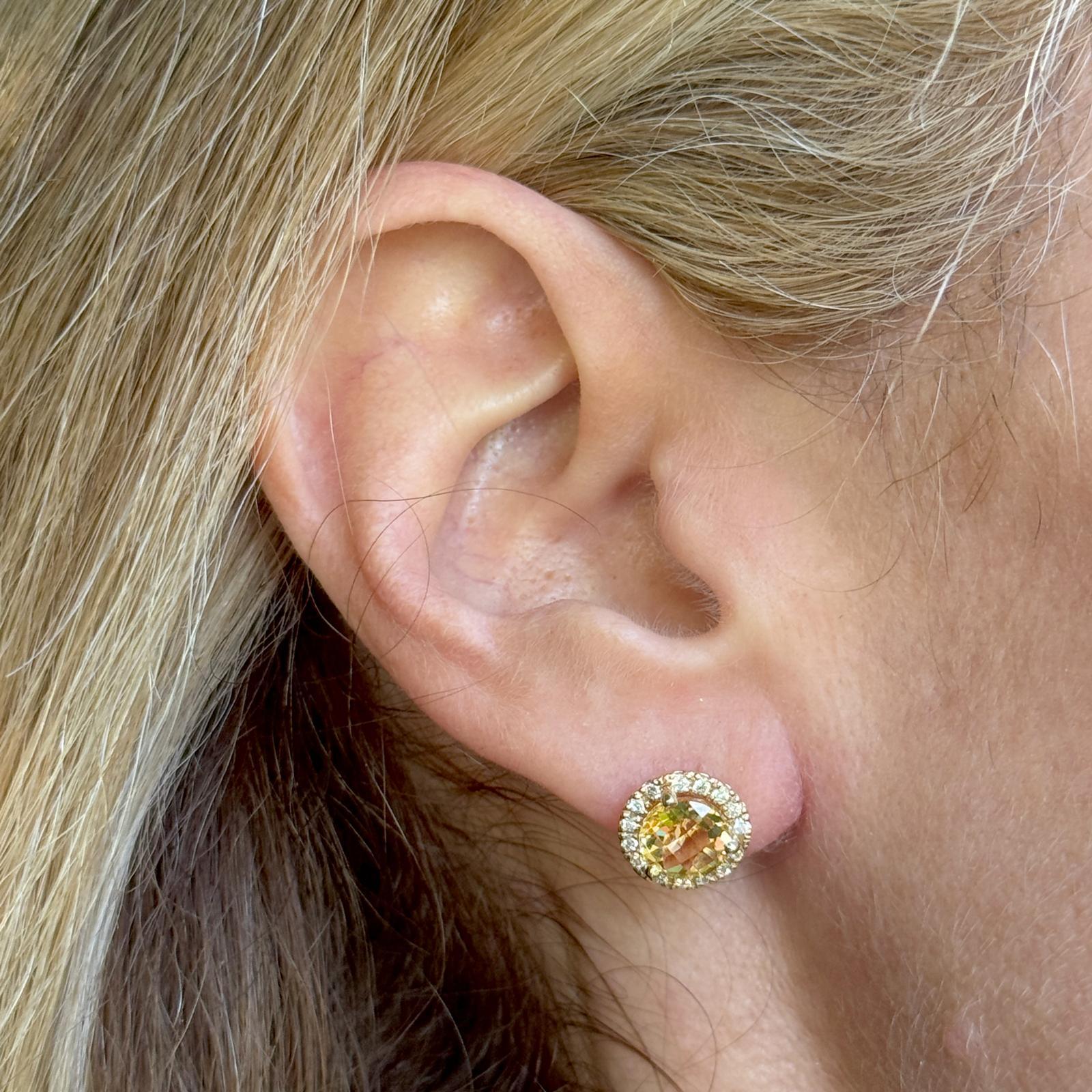 Ces boucles d'oreilles rayonnantes en or jaune 14 carats présentent en leur centre des citrines de 7 mm de taille ronde, entourées d'un halo étincelant de 30 diamants ronds de taille brillant totalisant environ 0,30 carat. Mesurant 10 mm de diamètre