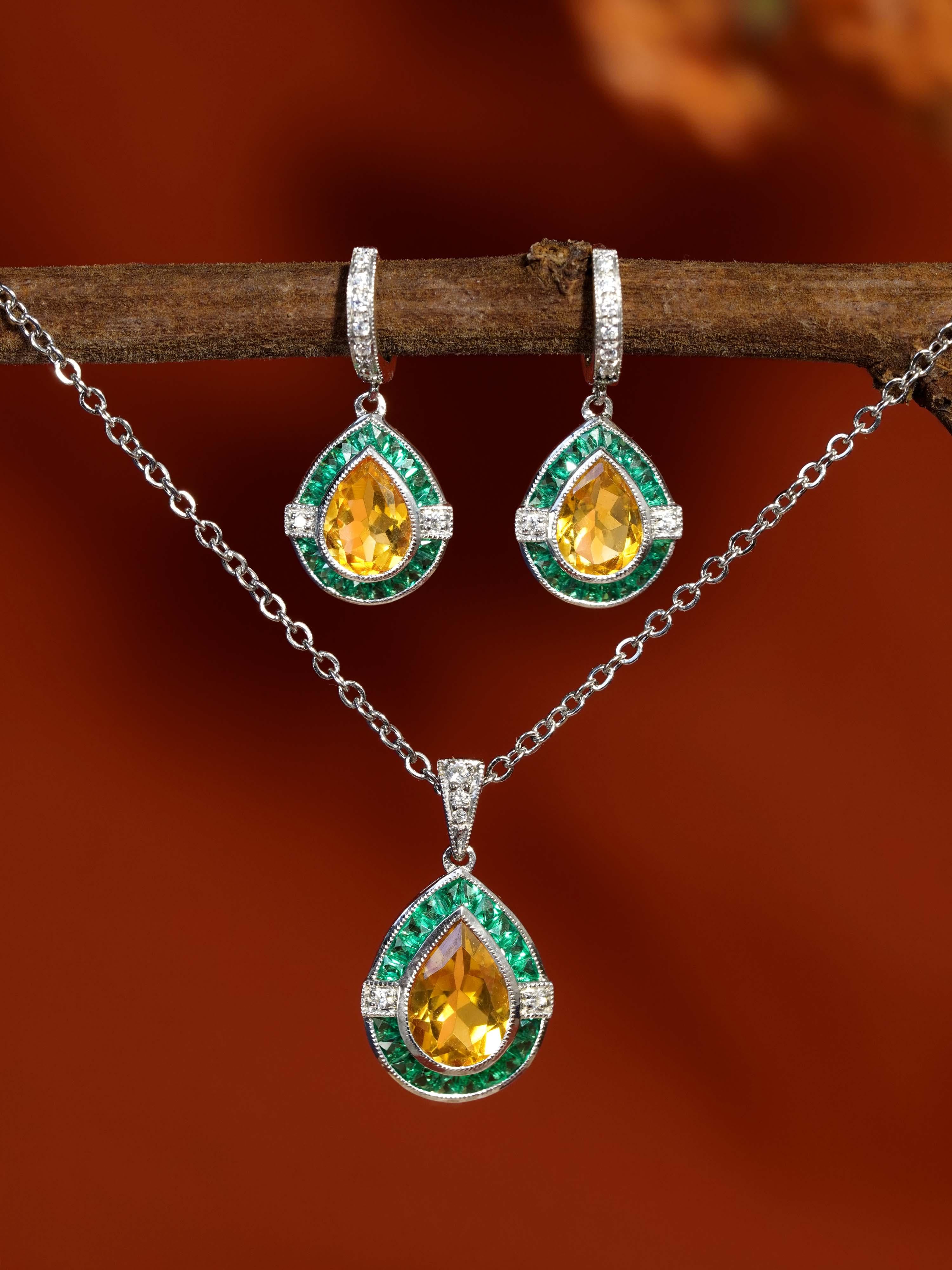 Un saphir jaune en forme de poire au centre, élégamment encadré par des émeraudes vibrantes et des diamants étincelants dans un design Art déco classique. Les boucles d'oreilles gouttes assorties complètent parfaitement le pendentif, ajoutant une