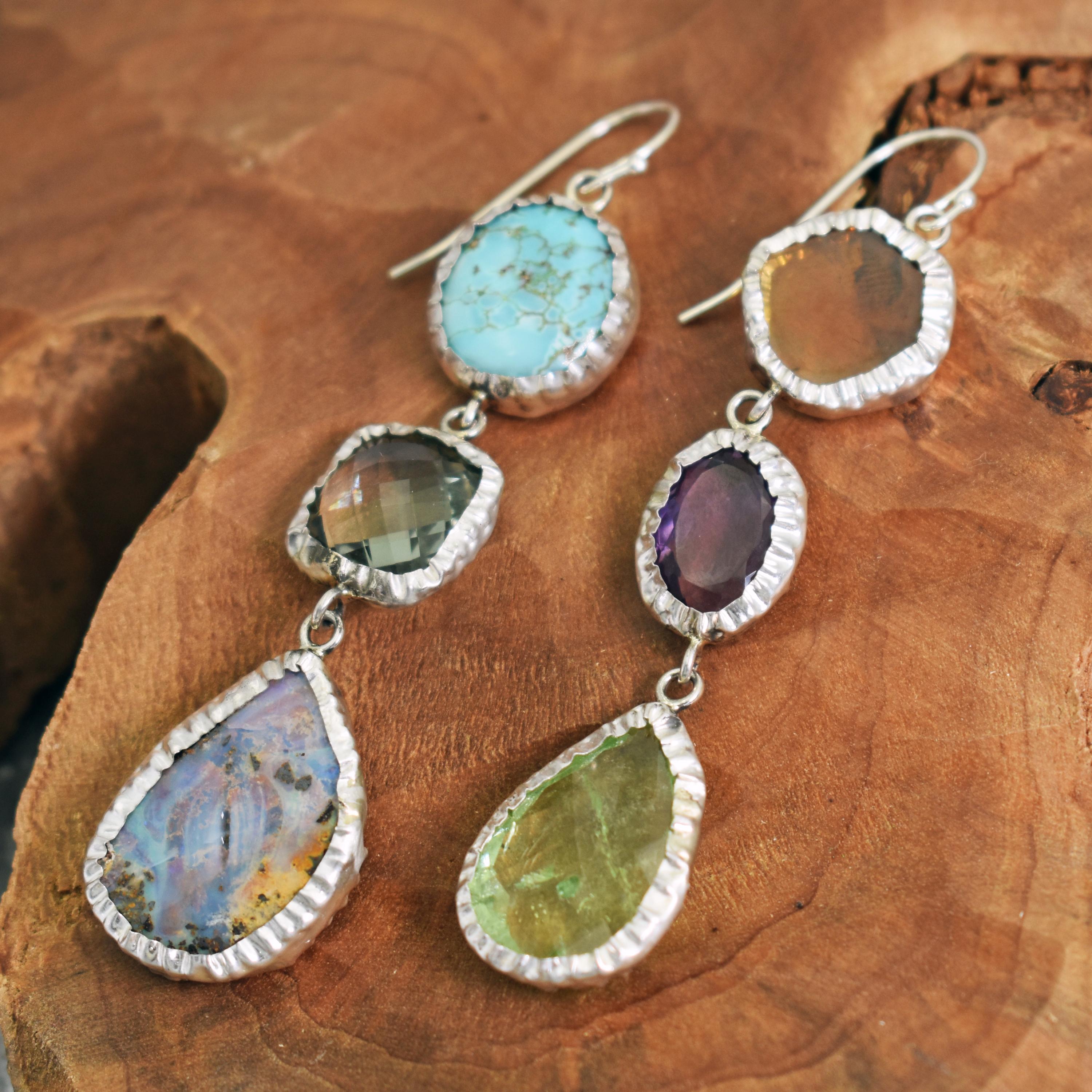 Three tier sterling silver asymmetrical dangle earrings featuring orange Tourmaline slice, Amethyst, yellowish green rose-cut Tourmaline, Carico Lake Turquoise, Green Quartz and Australian Boulder Opal gemstones. Dangle earrings are 3.13 inches in