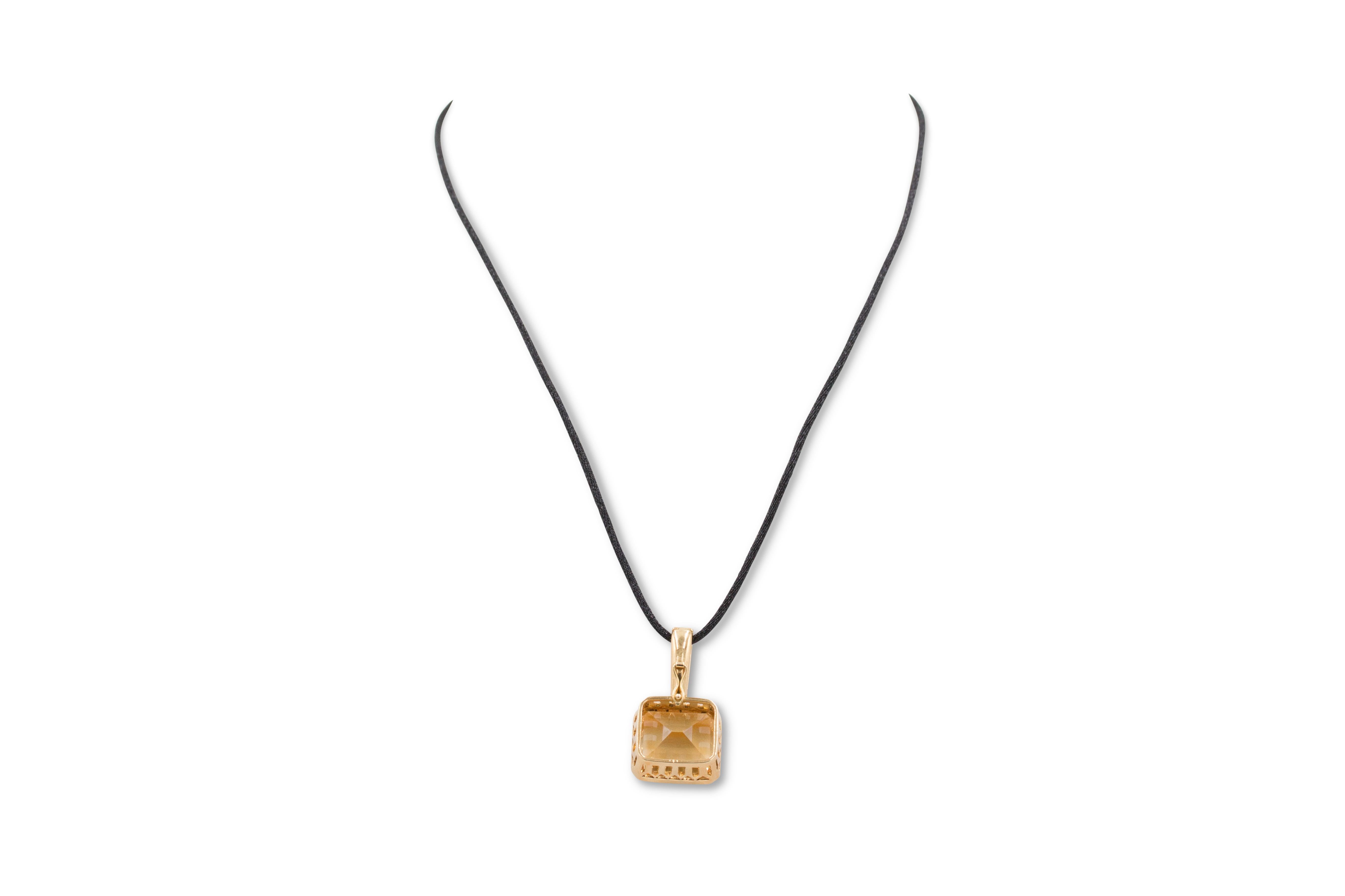 A lively rectangular step-cut citrine stone weighing an estimated 21 carats set in an 18 karat gold pendant. No markings or signatures present. The pendant hangs from a satin cord that is not original to this piece. Not presented with the original