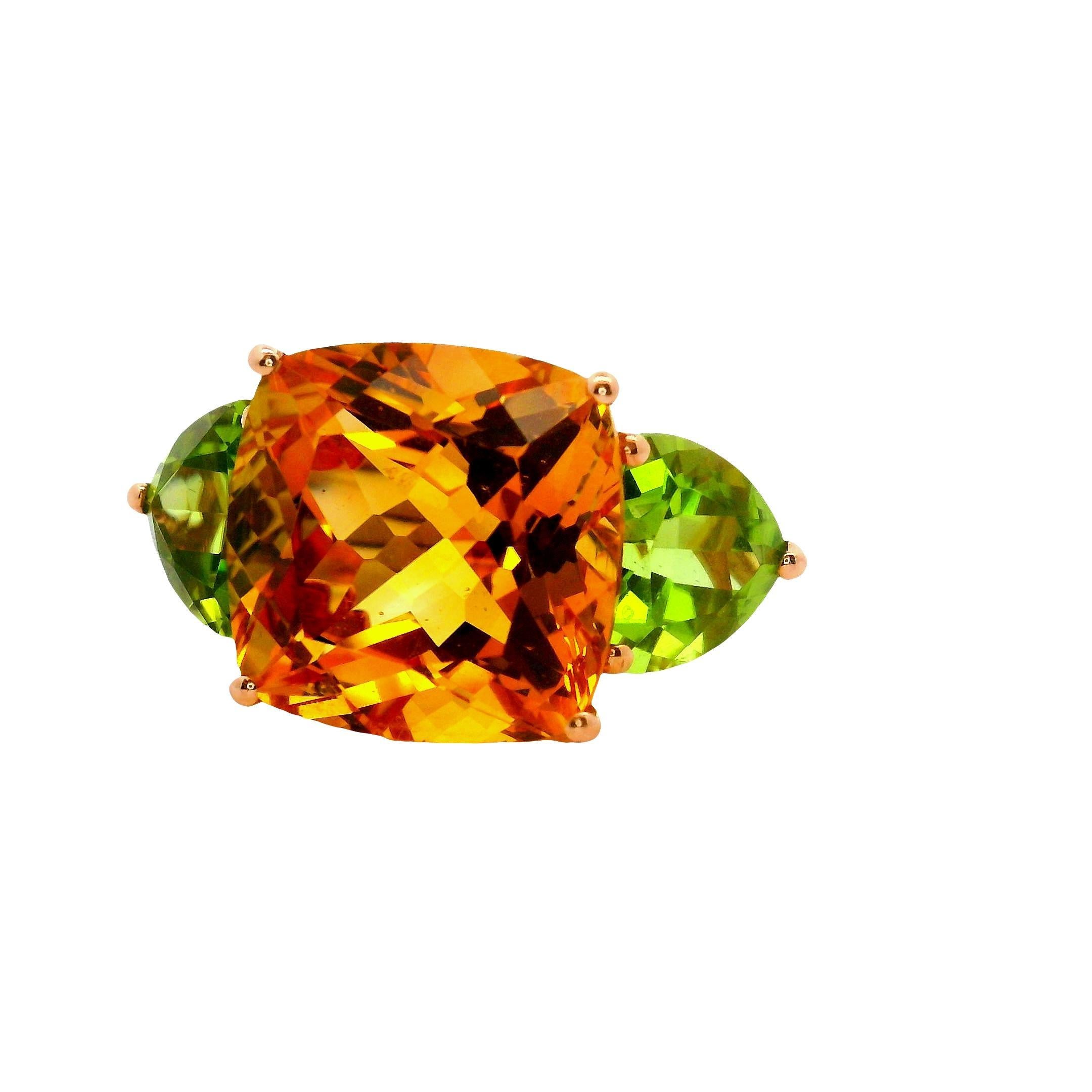 A striking three-stone ring featuring a cushion-cut citrine with a vibrant orange hue. Flanking the citrine are two heart-cut peridots, each displaying a vivid green color. Crafted in 14k rose gold, the ring presents a bold contrast of colors and