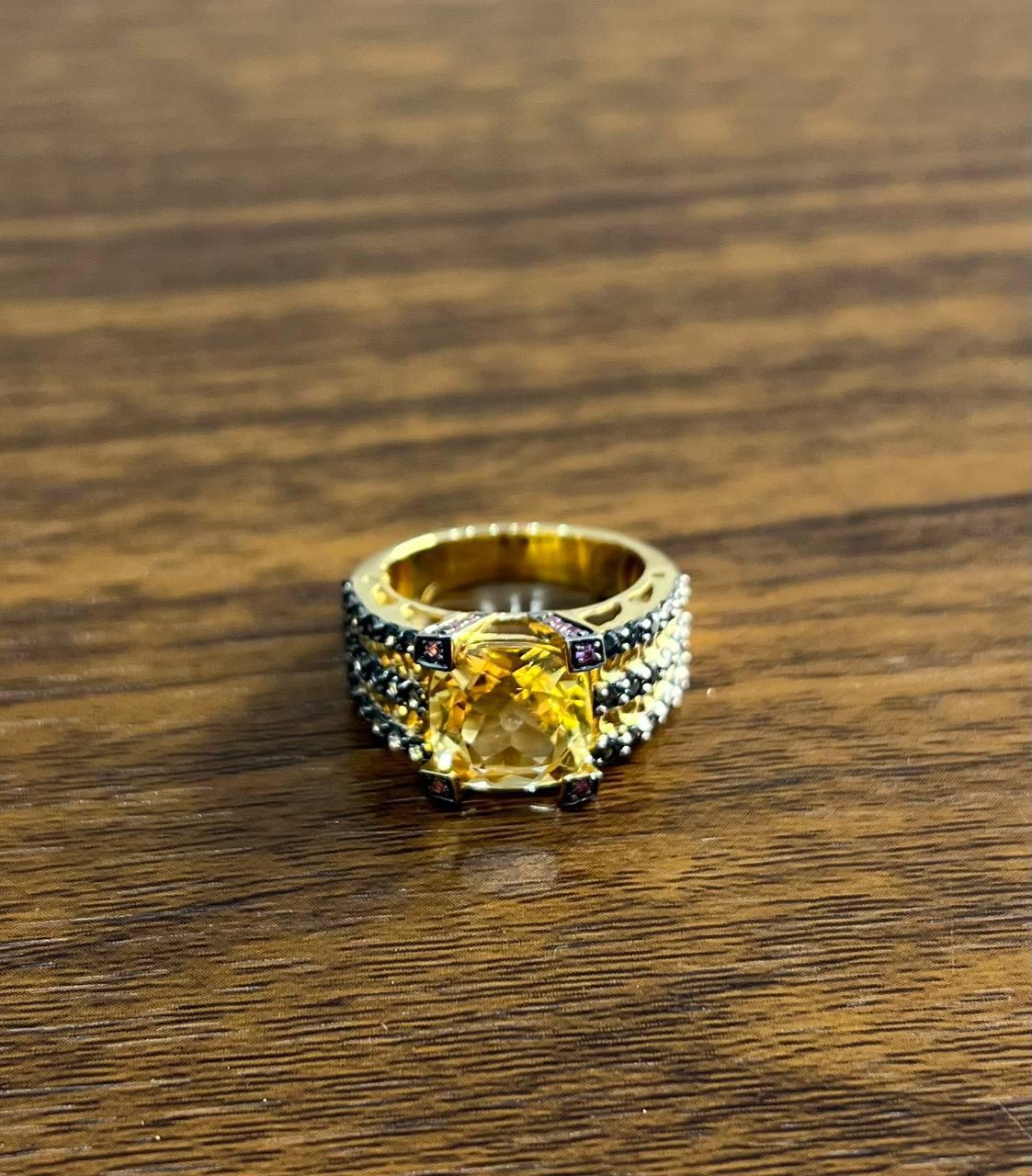 A striking statement ring featuring a large, vibrant orange amber at its center.

The ring is adorned with intricate multi-stone detailing along the band, enhancing its bold and luxurious appearance.

Crafted with precision, this exquisite piece is