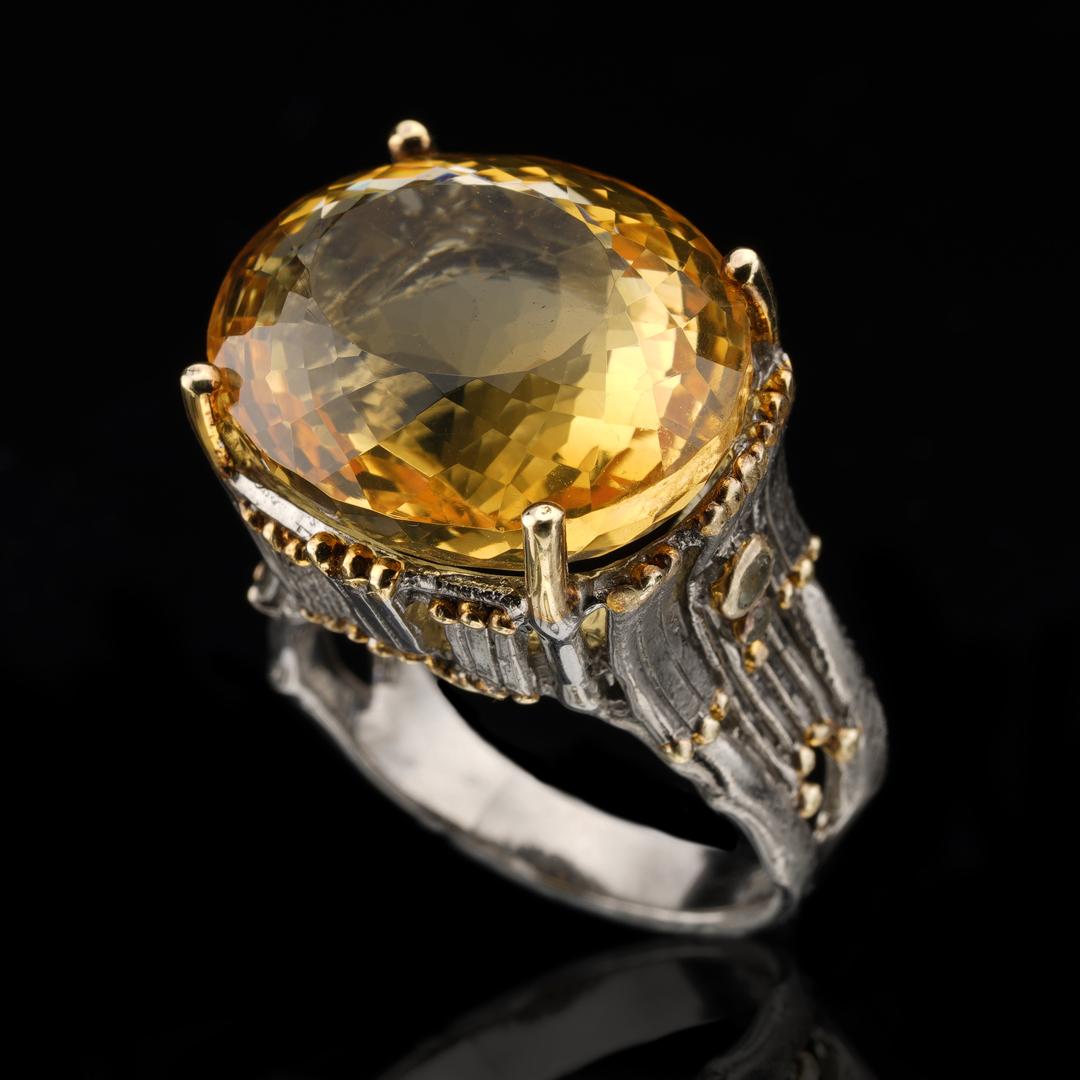 This colorful, sparkling statement piece features a fiery, dimensional oval-cut citrine in a hand-tooled rhodium plated sterling silver band with a stately, modern design featuring gold leaf ornamentation and two round-cut green amethysts or