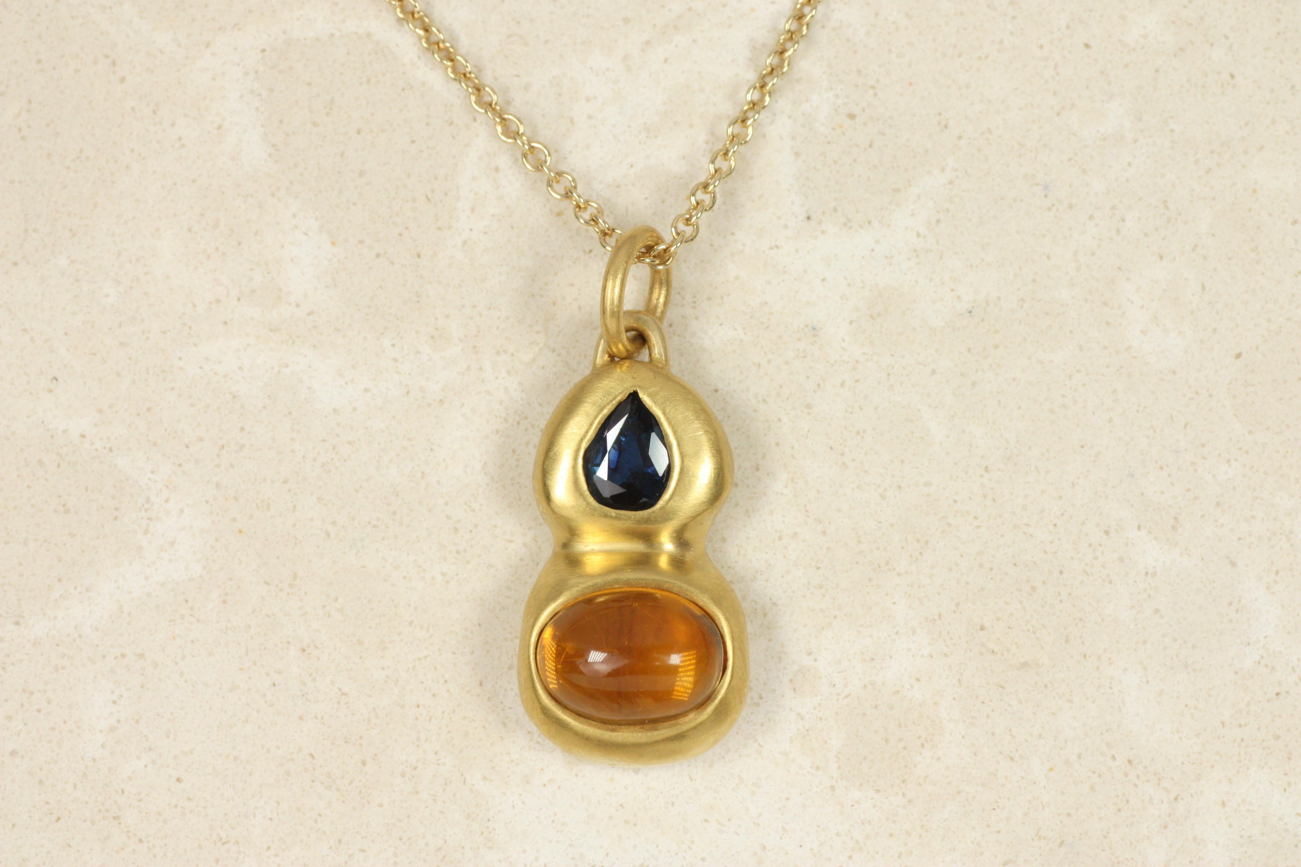A cabochon cut citrine and pear-shaped faceted blue sapphire are paired in this two-stone bezeled pendant, crafted in 22K yellow. The unique shapes and raw hammered finish make for a truly one-of-a-kind piece, made by Bracken Jewelers in Los