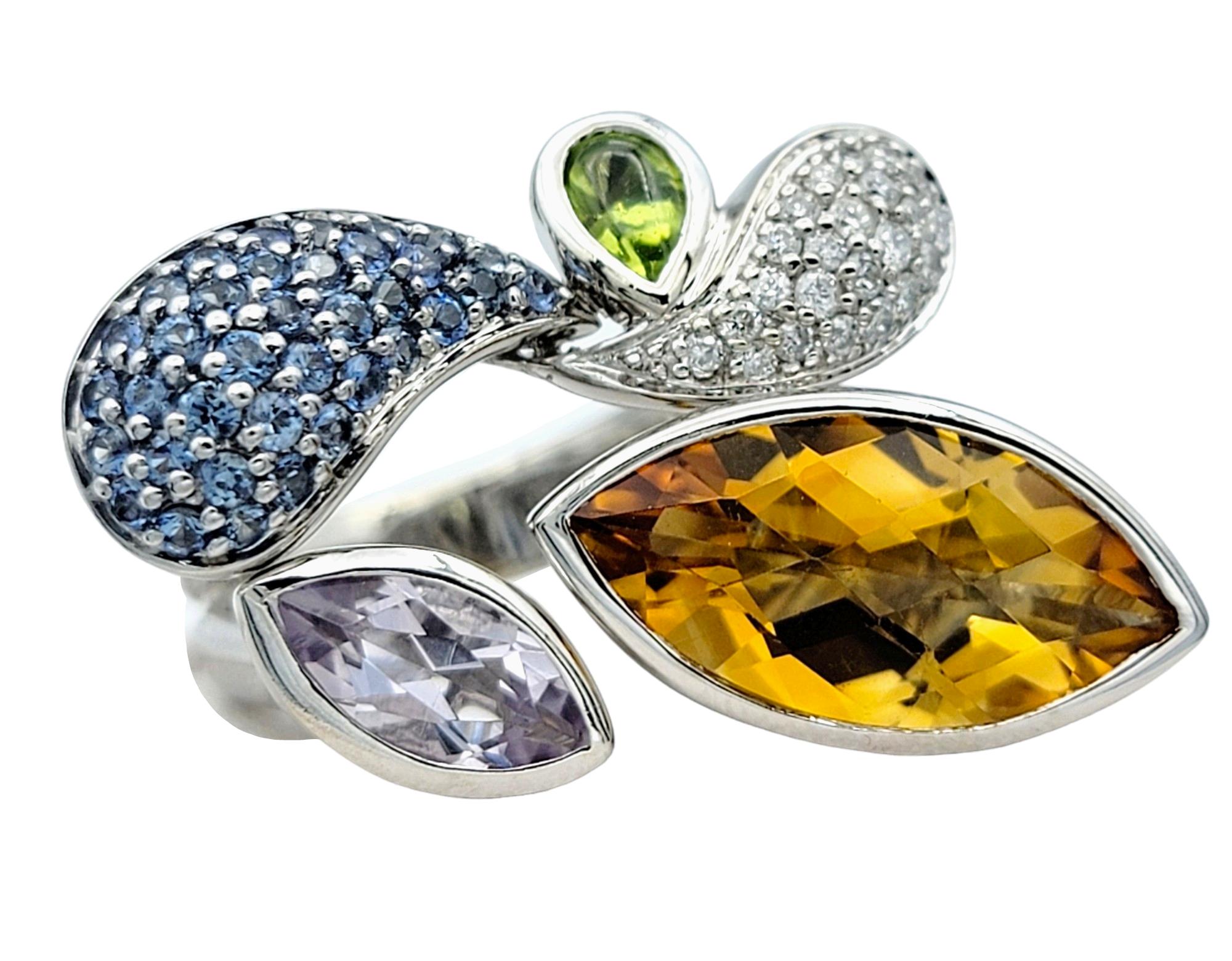 Ring Size: 7

Exuding vibrant charm and contemporary elegance, this multi-colored gemstone cocktail ring is a true statement piece. Set in gleaming 18 karat white gold, it showcases a captivating array of gemstones in various shapes and hues,