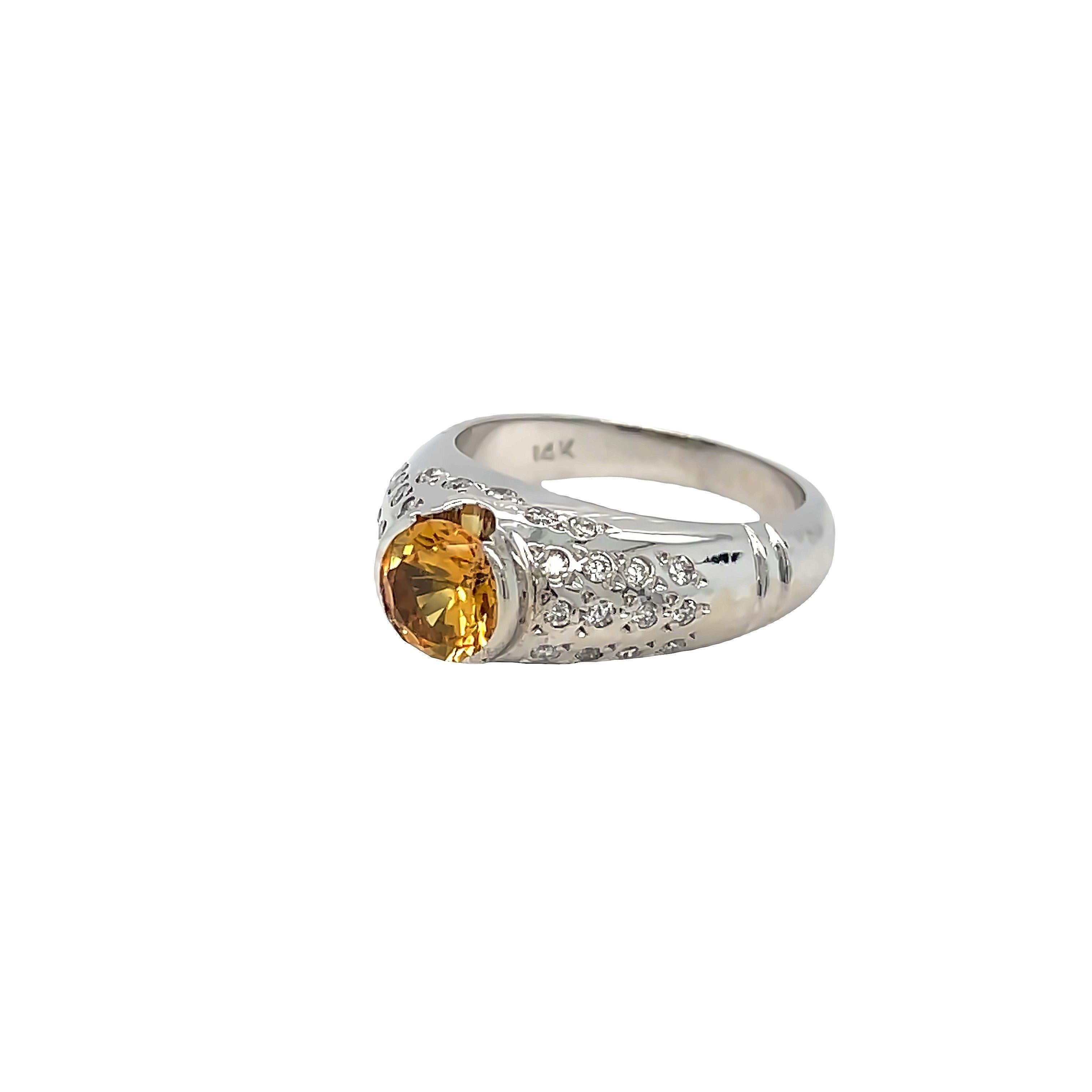 Elegant and contemporary, this 14K White Gold Citrine Diamond Ring features a stunning round Citrine weighing approximately 1.30 carats. Irradated Citrine is beautifully showcased in a raised half-bezel setting, complemented by a dome setting