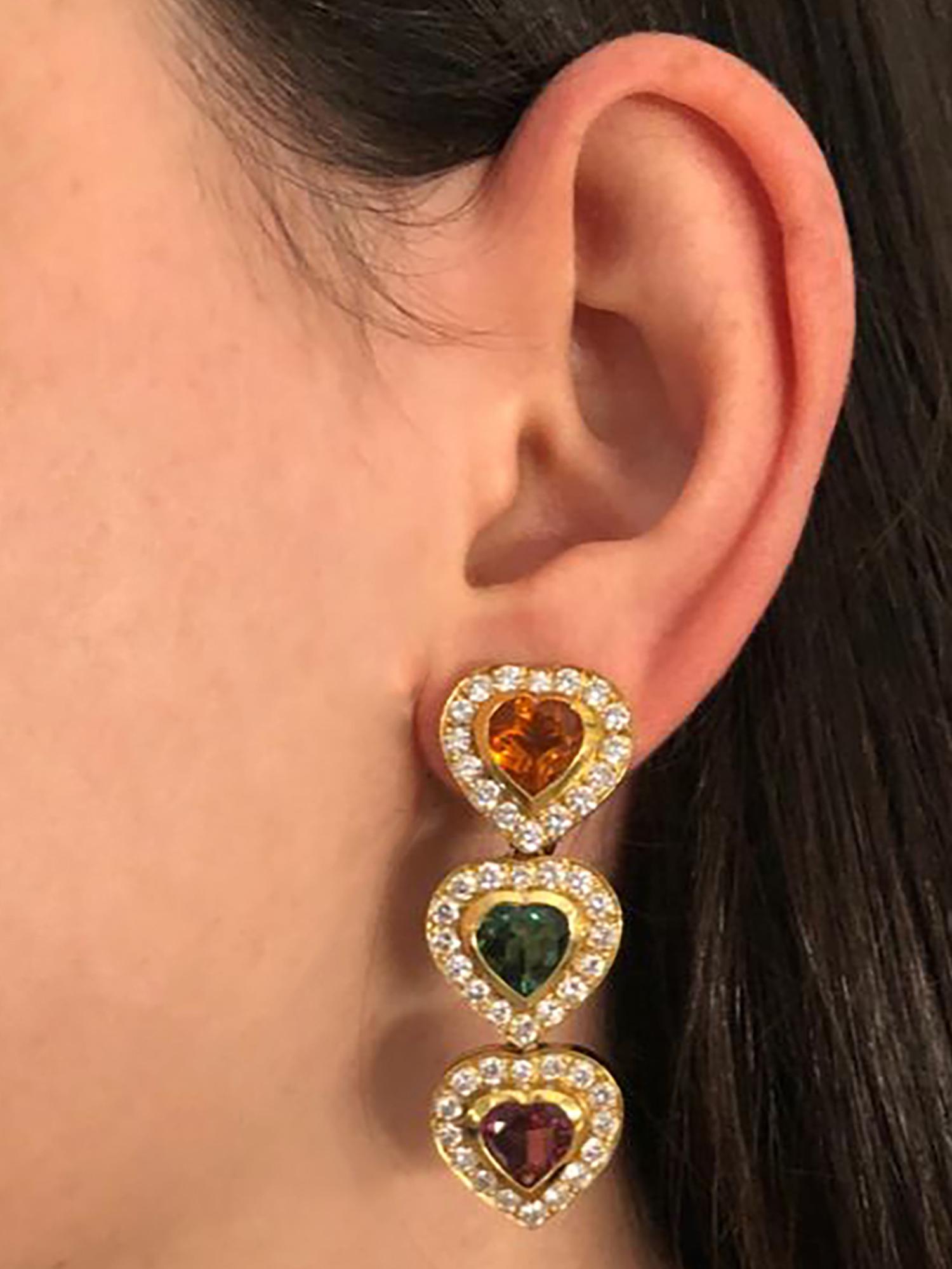 Enchanting dangle earrings crafted in 18 karat yellow gold, featuring two citrine hearts weighing approximately 4 carats total, two rubellite tourmaline hearts weighing approximately 4 carats total, and two green tourmaline hearts weighing