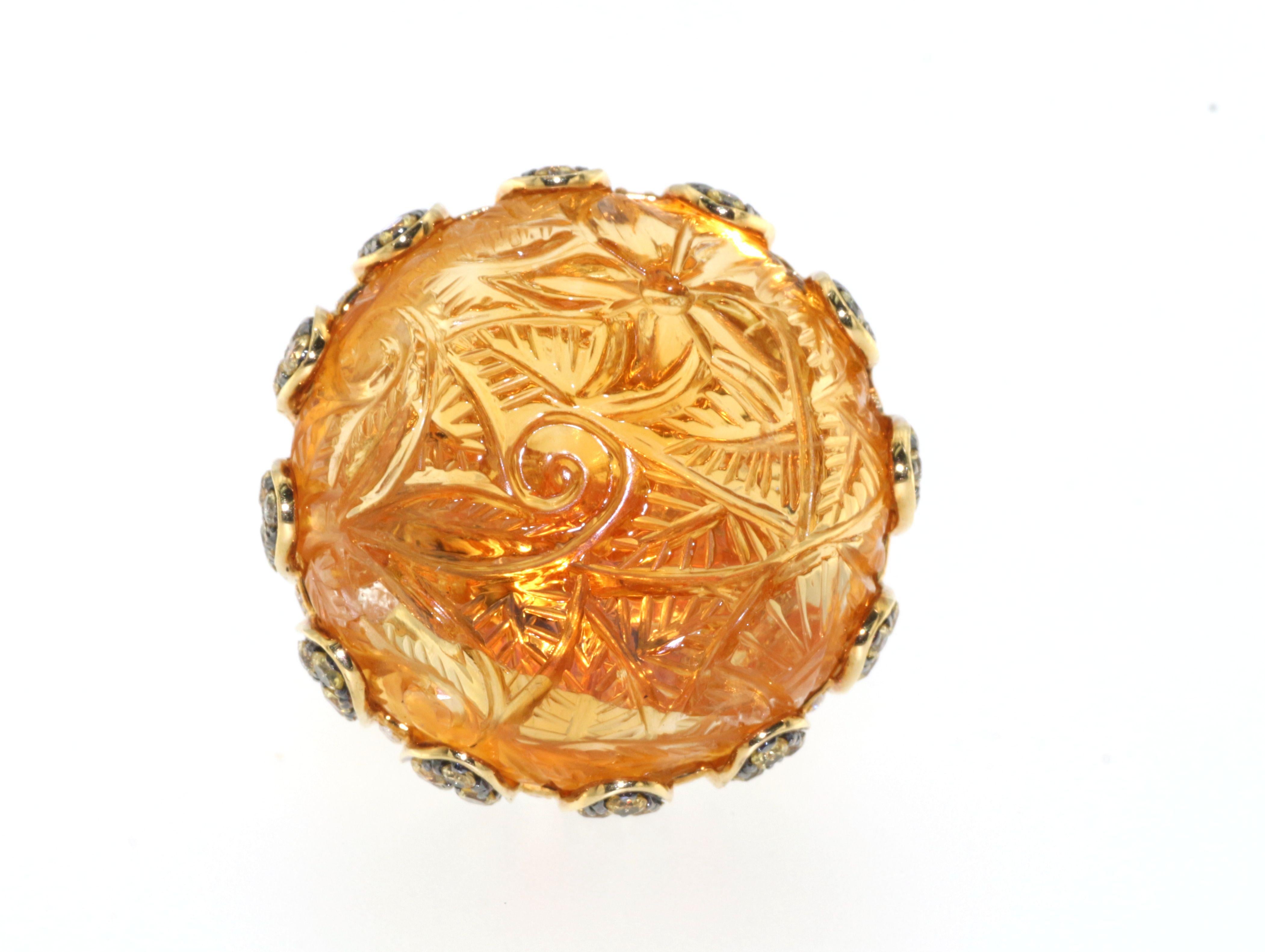 Introducing a stunning 46Ct Carved Citrine Yellow Sapphire and Diamond Cocktail Ring in 18kt Yellow Gold, perfect for adding a bold and beautiful statement to any outfit. The exquisite carved citrine centerpiece is surrounded by an array of vibrant