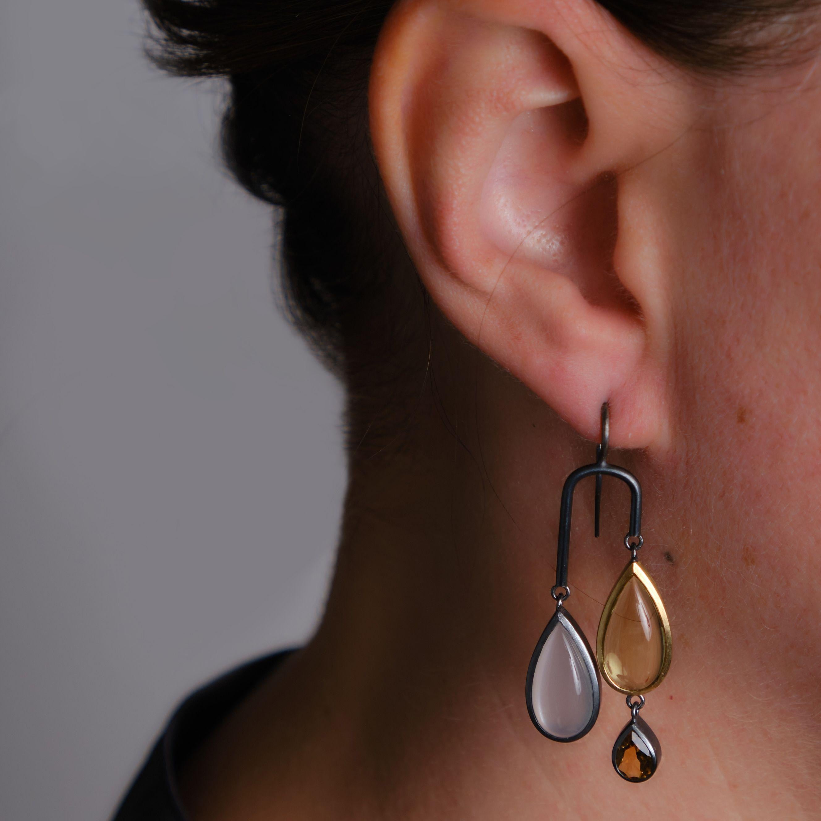 These very contemporary oxidised sterling silver and 18K gold drop pierced earrings playfully feature a brilliantly balanced combination of cabochon and faceted citrine, lemon quartz, moonstone, and rock crystal. 
These earrings are designed and