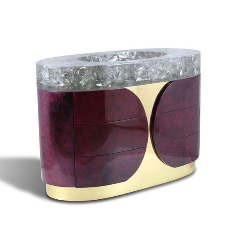 Un mueble de baño vibrantemente atrevido que exhibe una mezcla excepcional de materiales nobles y artesanía de lujo. La base de zócalo de inspiración Art Decó, revestida de latón pulido, se extiende por la cara central, complementando el cuerpo, que