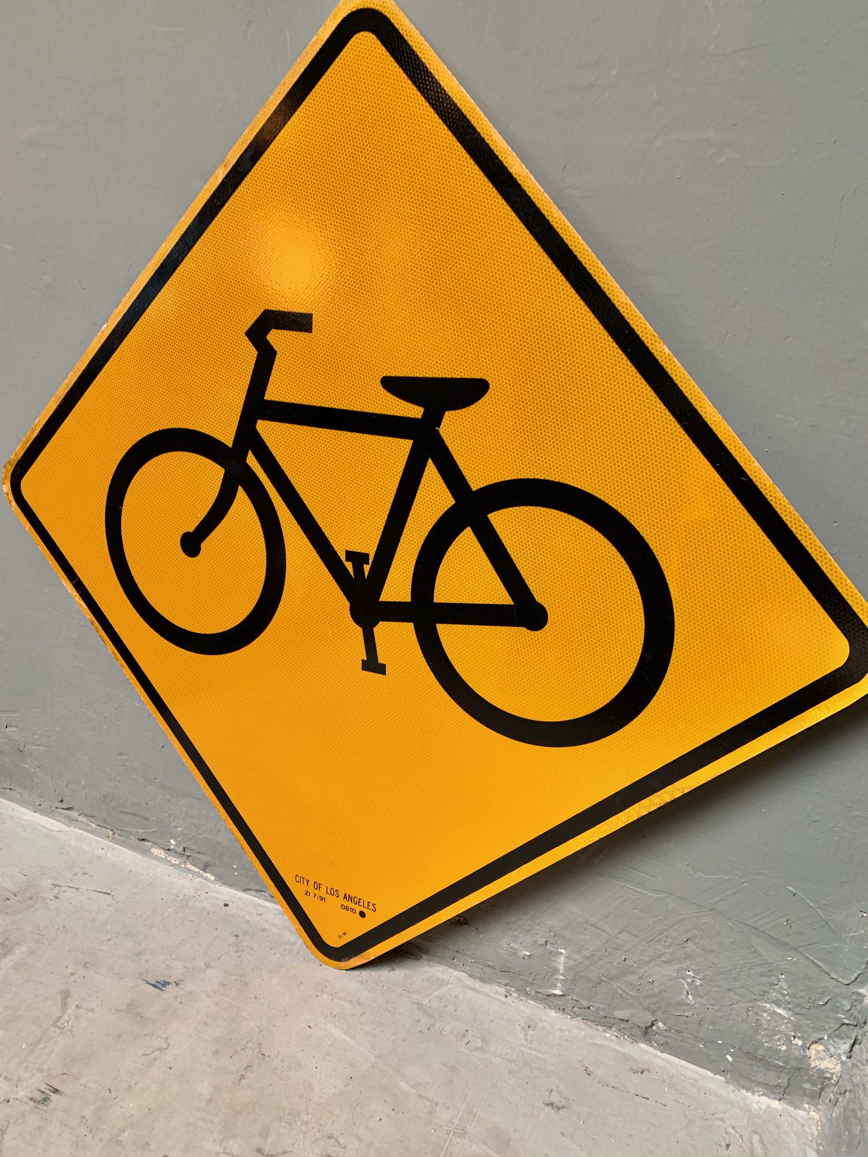 Massive yellow bike sign from Los Angeles. Large black bike on a yellow reflective background. Marked 'City of Los Angeles' and 1991 on the front. Great coloring and subject matter. Measures: 41
