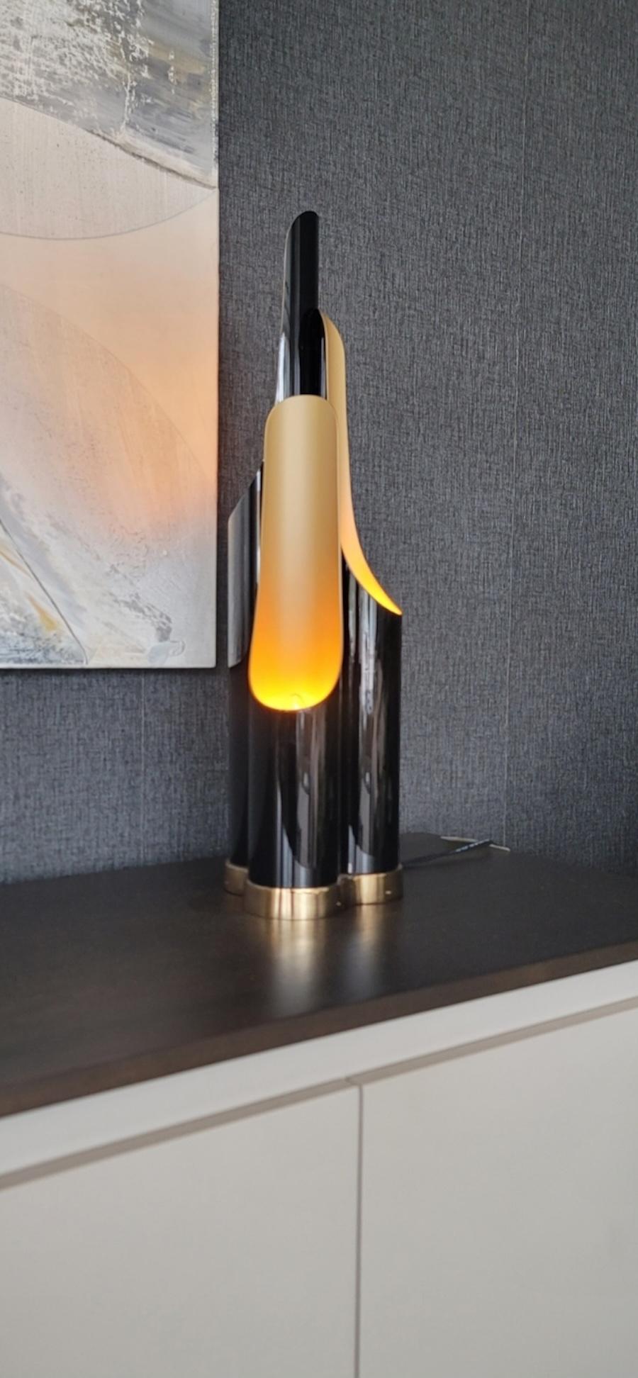 Lampe de bureau élégante et particulière avec trois points lumineux de style contemporain pour les chambres et les espaces communs.
 
Lampe à structure tubulaire en métal bicolore avec extérieur en émail noir, ( noir brillant à l'extérieur et doré à