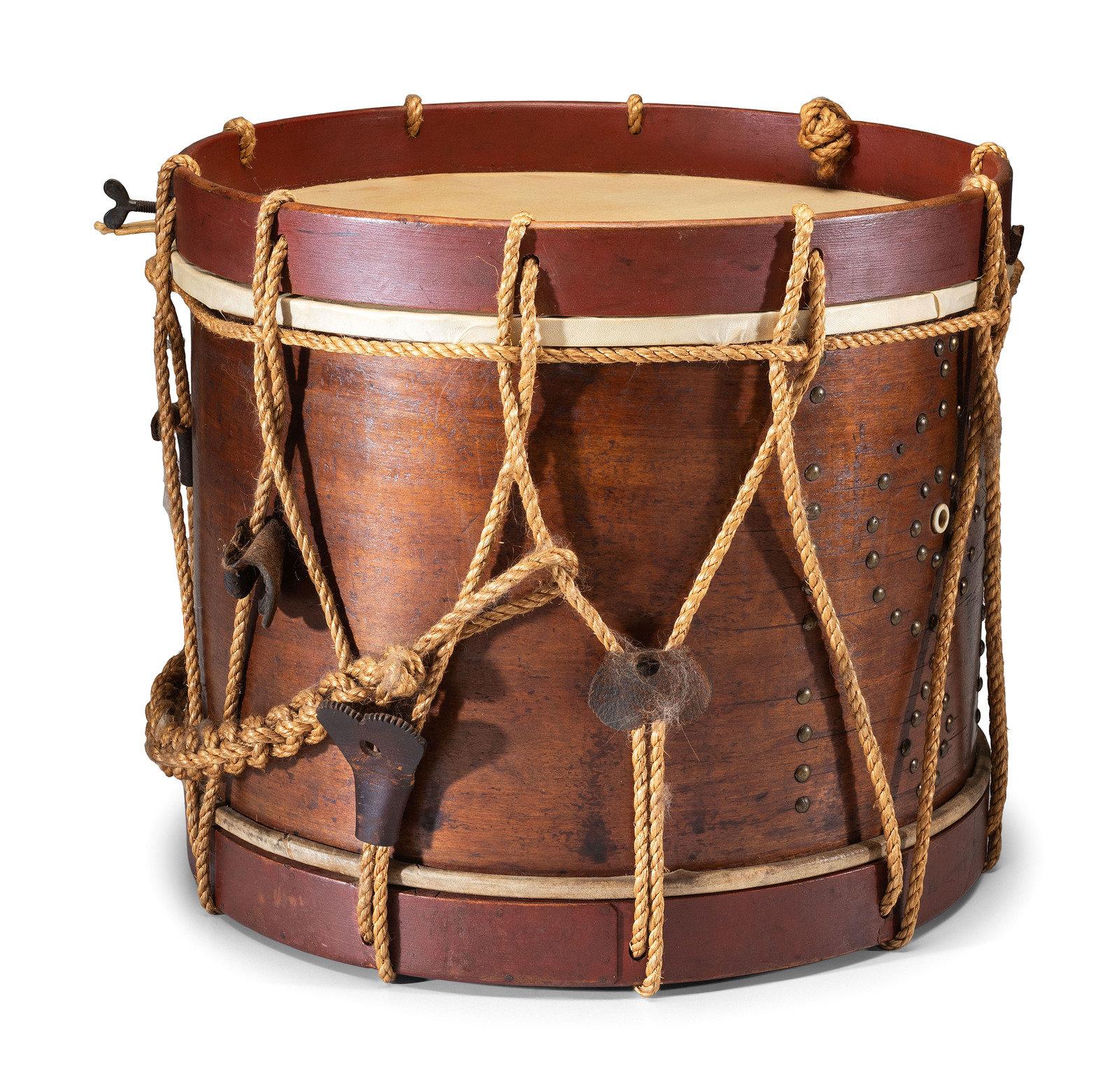Presented is an original Civil War-era side drum with a pair of wooden drumsticks. This is a rope tension drum with a wooden body, ropes, and leather tabs. An iron tack pattern surrounds the drum hole. The drum's hoops are painted a deep red. The
