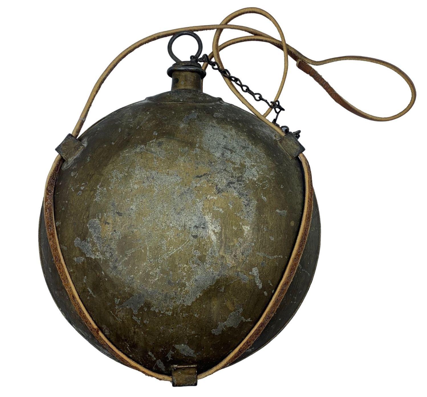 Presented is an original Civil War-era tin canteen. A classic example of the 1858 model “smoothside” canteen, this example retains its original pull ring, cork stopper, and linked chain stopper attachment. The body of one side of the tin canteen was