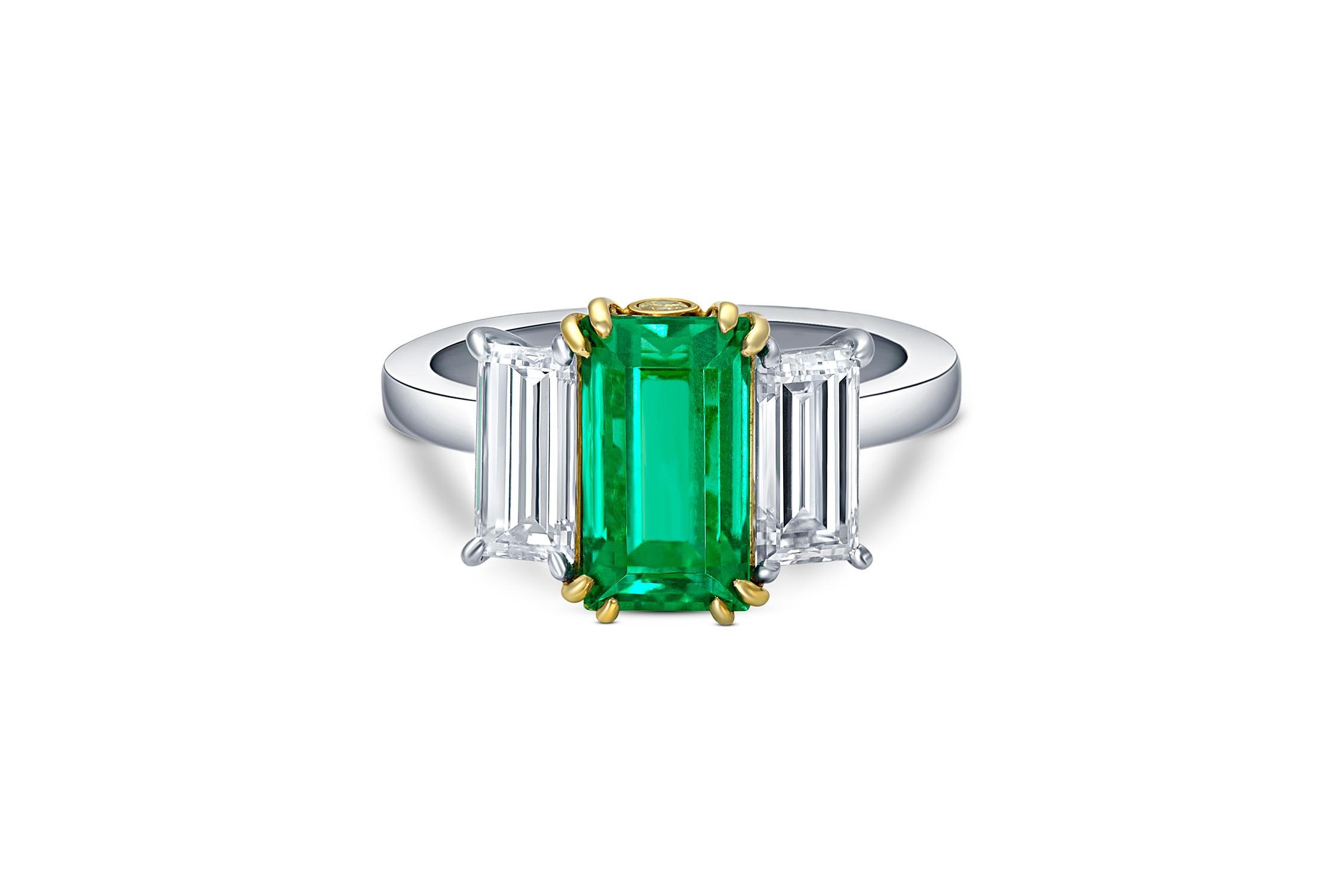 Ein außergewöhnlicher 2,22 ctw Smaragd-Mittelstein, flankiert von prächtigen Baguette-Diamanten von insgesamt 1,48 ctw. Die elegante Galerie aus 18-karätigem Gelbgold und Platin zeigt auf jeder Seite einen runden gelben Diamanten im Brillantschliff.