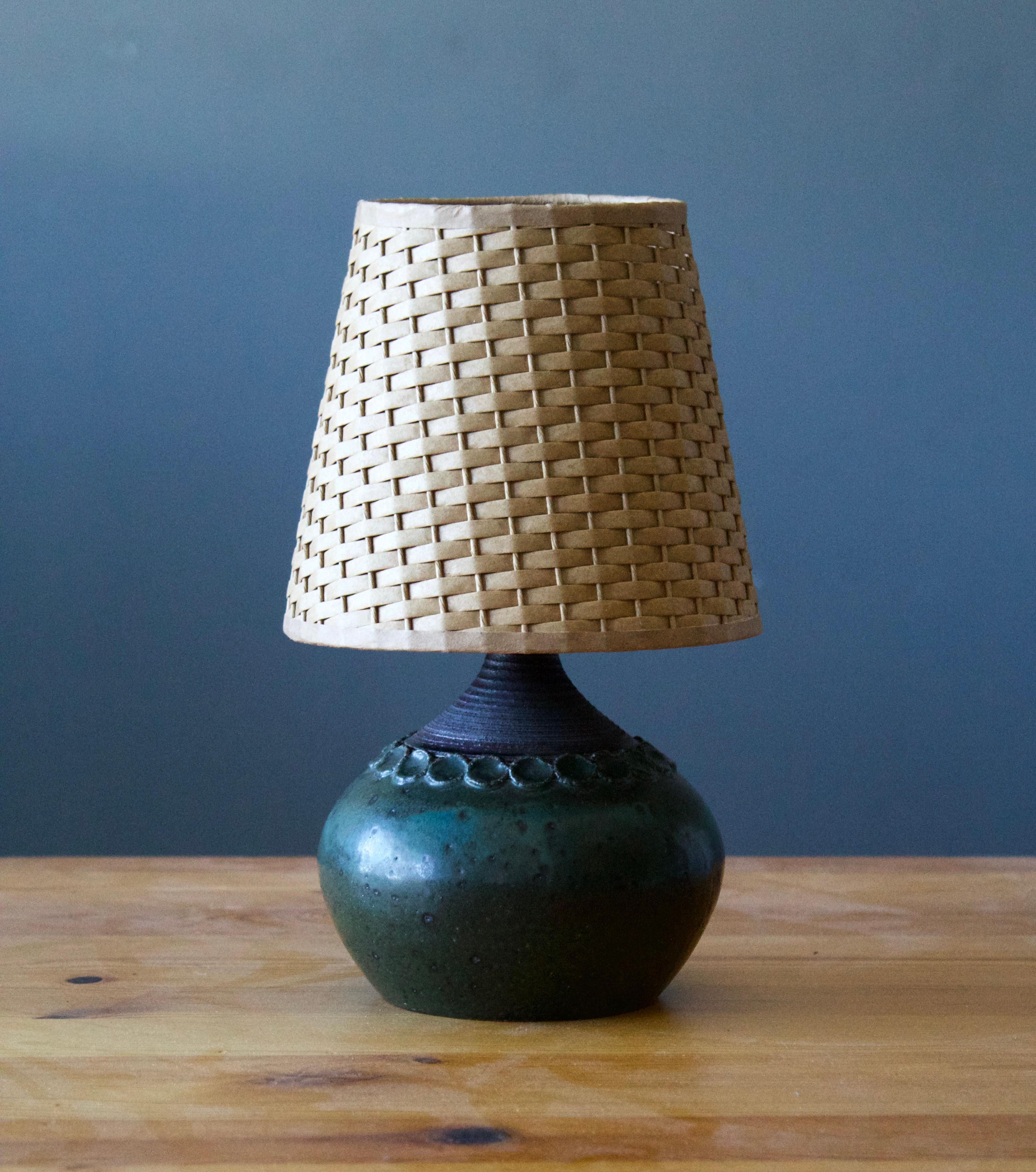 A small table lamp. Produced and designed by Claes Thell, Artist's studio, Höganäs, Sweden.

In glazed stoneware. Stated dimensions exclude lampshade. Height includes socket. Illustrated rattan lampshade can be included upon request.