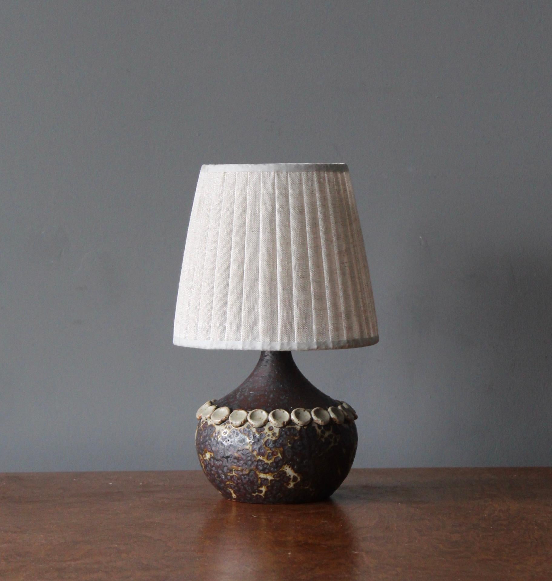A table lamp. Produced and designed by Claes Thell, Artist's studio, Höganäs, Sweden.

In glazed stoneware. Stated dimensions exclude lampshade. Height includes socket. Illustrated rattan lampshade can be included upon request.