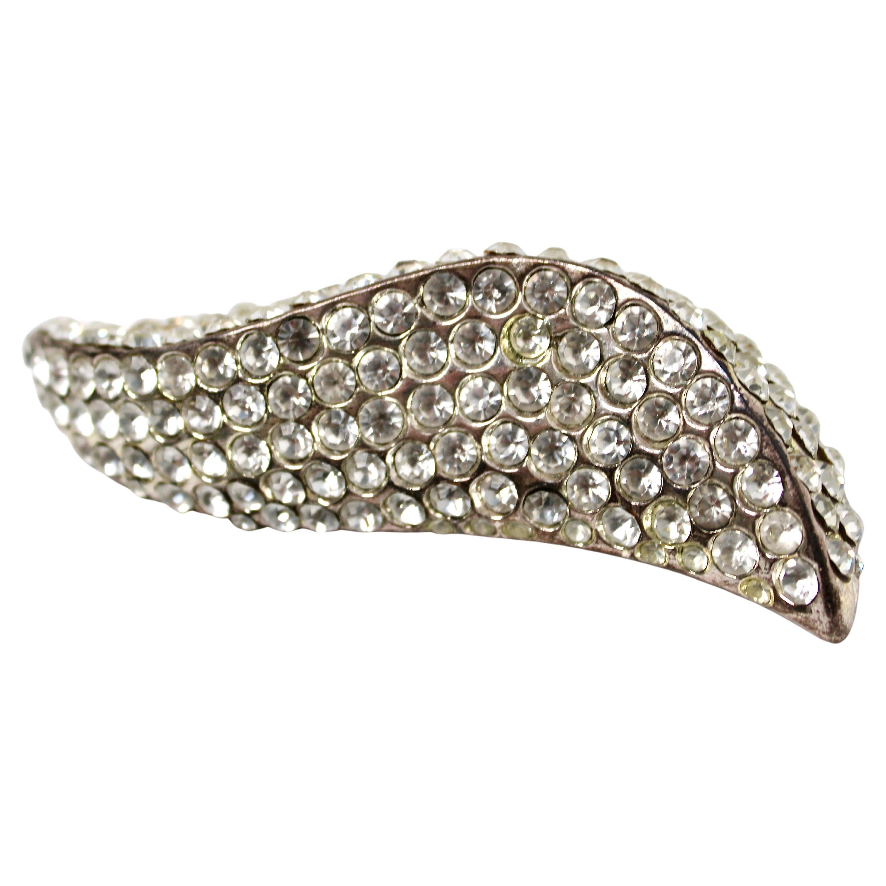 Die Claire Deve Leaf Statement-Brosche mit Strasssteinen in Silber um 1980 ist ein atemberaubendes Vintage-Accessoire, das zeitlose Eleganz und aufwändige Handwerkskunst ausstrahlt. Die aus silberfarbenem Metall gefertigte Brosche zeichnet sich
