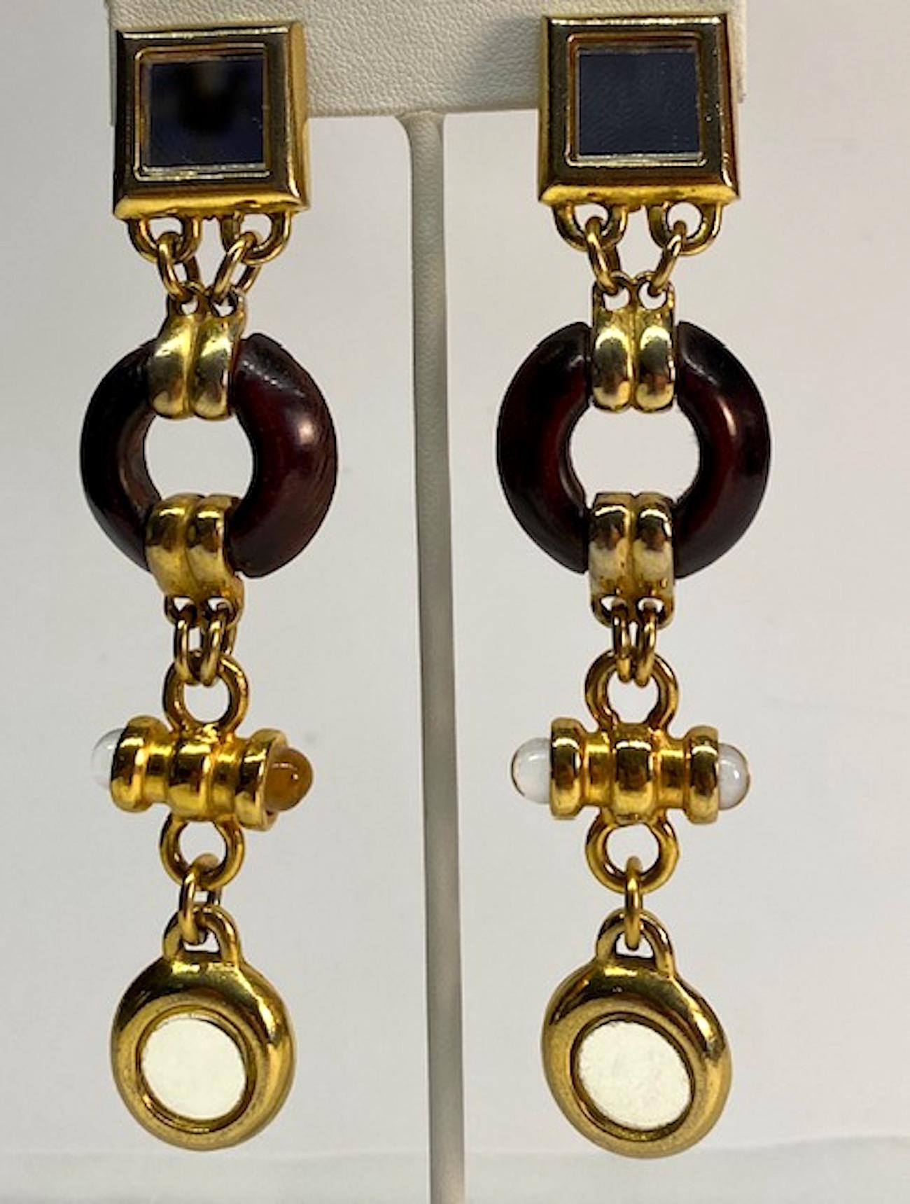 A striking pair of long pendant earrings by French designer Claire Deve. The earrings not only have mirror glass pieces in the gold tone setting, but also a wood ring and glass bead accents. A wonderful combination of materials beautifully