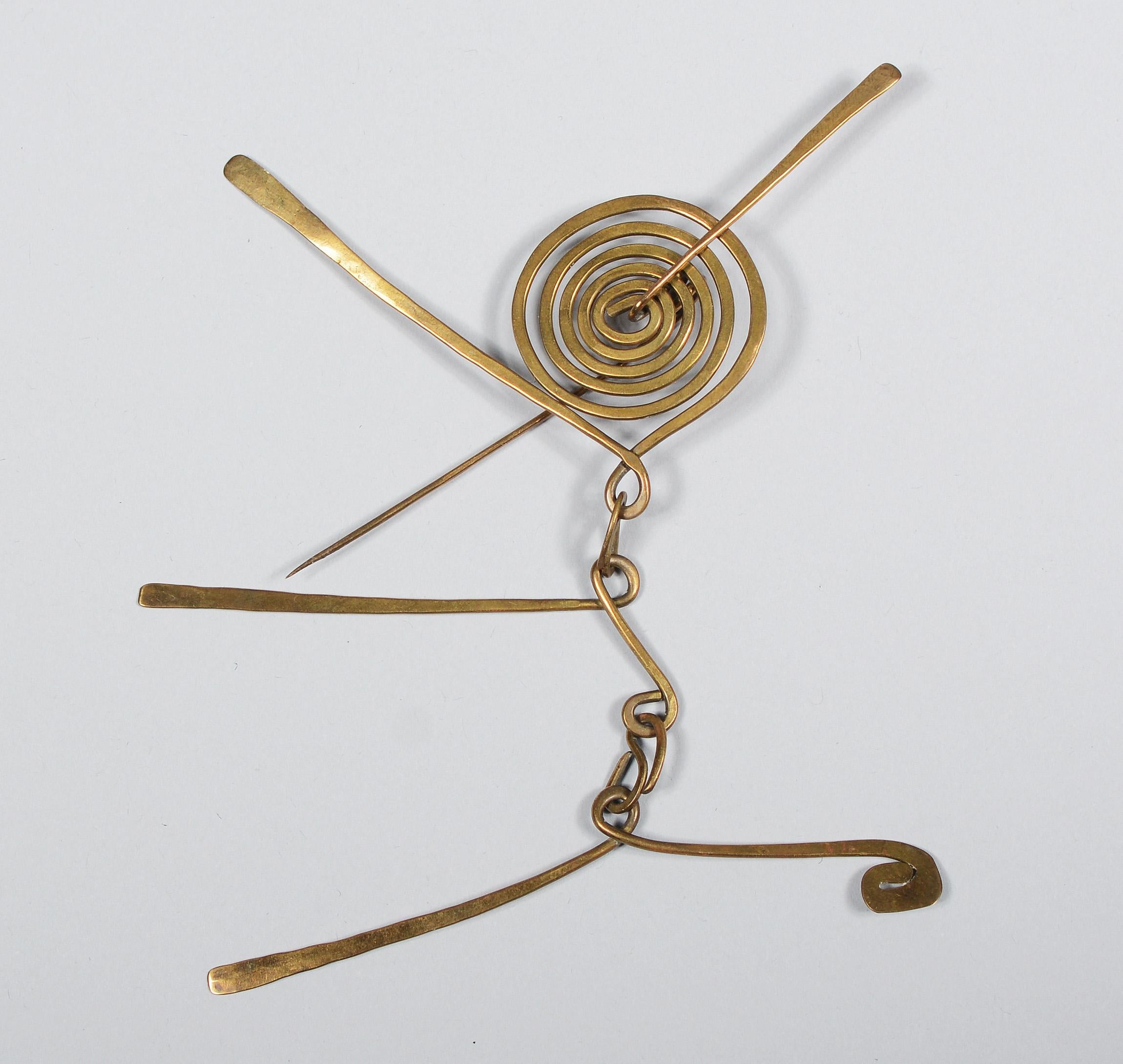 Articulated brass brooch and earrings by the artist Claire Falkenstein. The spiral on the brooch rotates on the pin that pierces the through the center of it. The arms below are like a small mobile. On one pair of earrings the inner spiral rotates