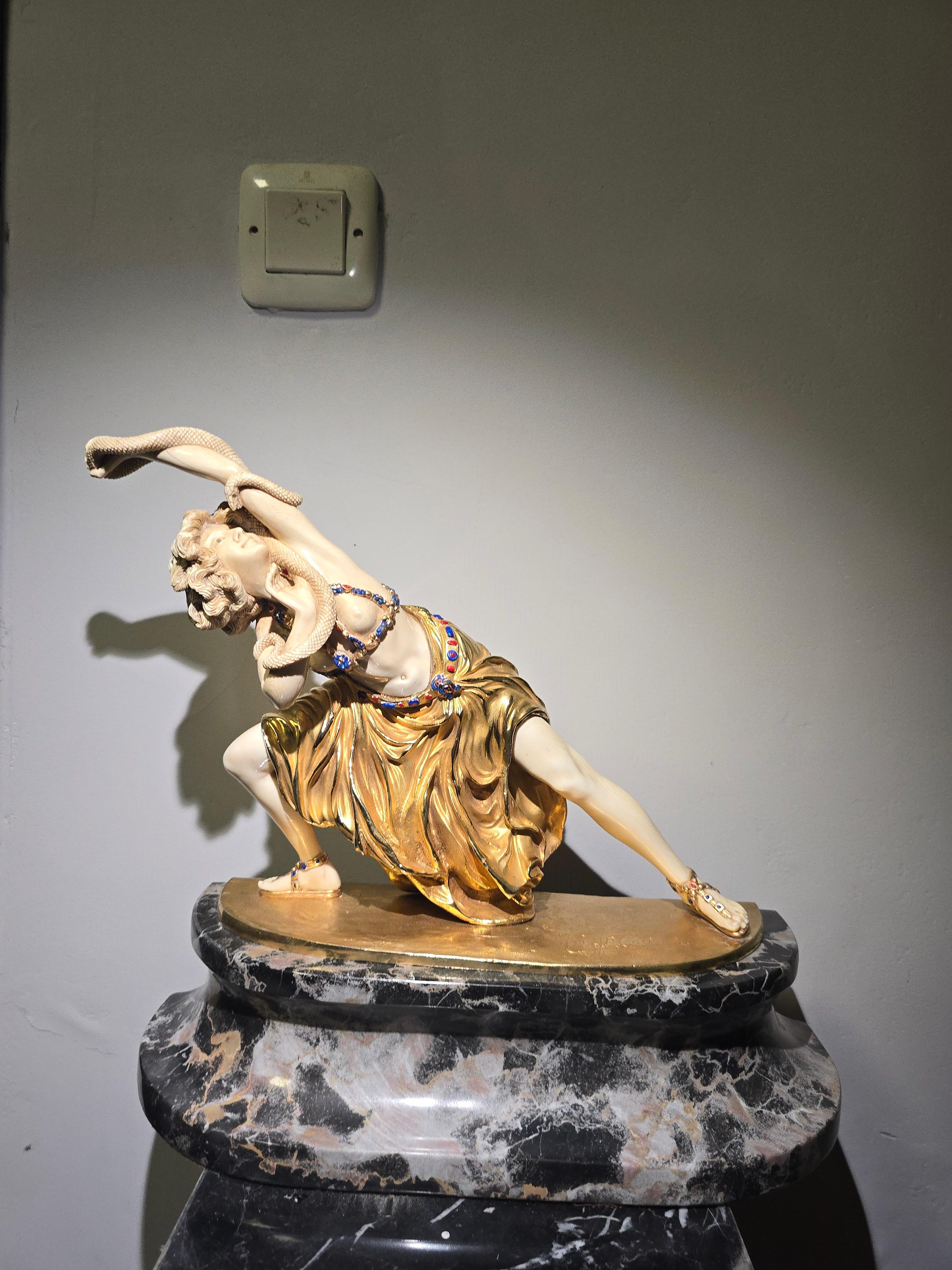 A stunning bronze sculpture by Claire J.R. Colinet, featuring a patinated, gilded, and cold-painted bronze figure of an exotic dancer with a snake. This 20th-century Art Deco piece showcases intricate detailing, with enamel accents on the dancer's