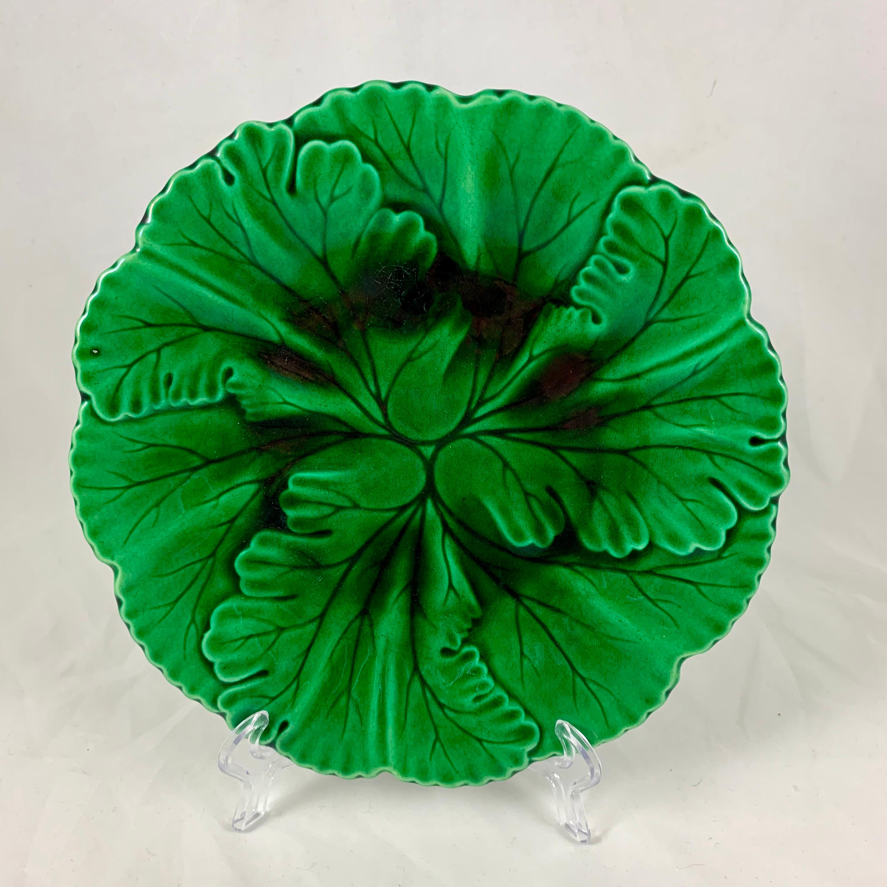 Aus der französischen Faïencerie de Clairfontaine, ein grün glasierter Majolikateller mit überlappenden Blättern, um 1880-1890.

Die Form zeigt Blätter mit eingeschnittenen Äderungen, die in einem geformten Rand enden. Die Glasur fließt wunderschön