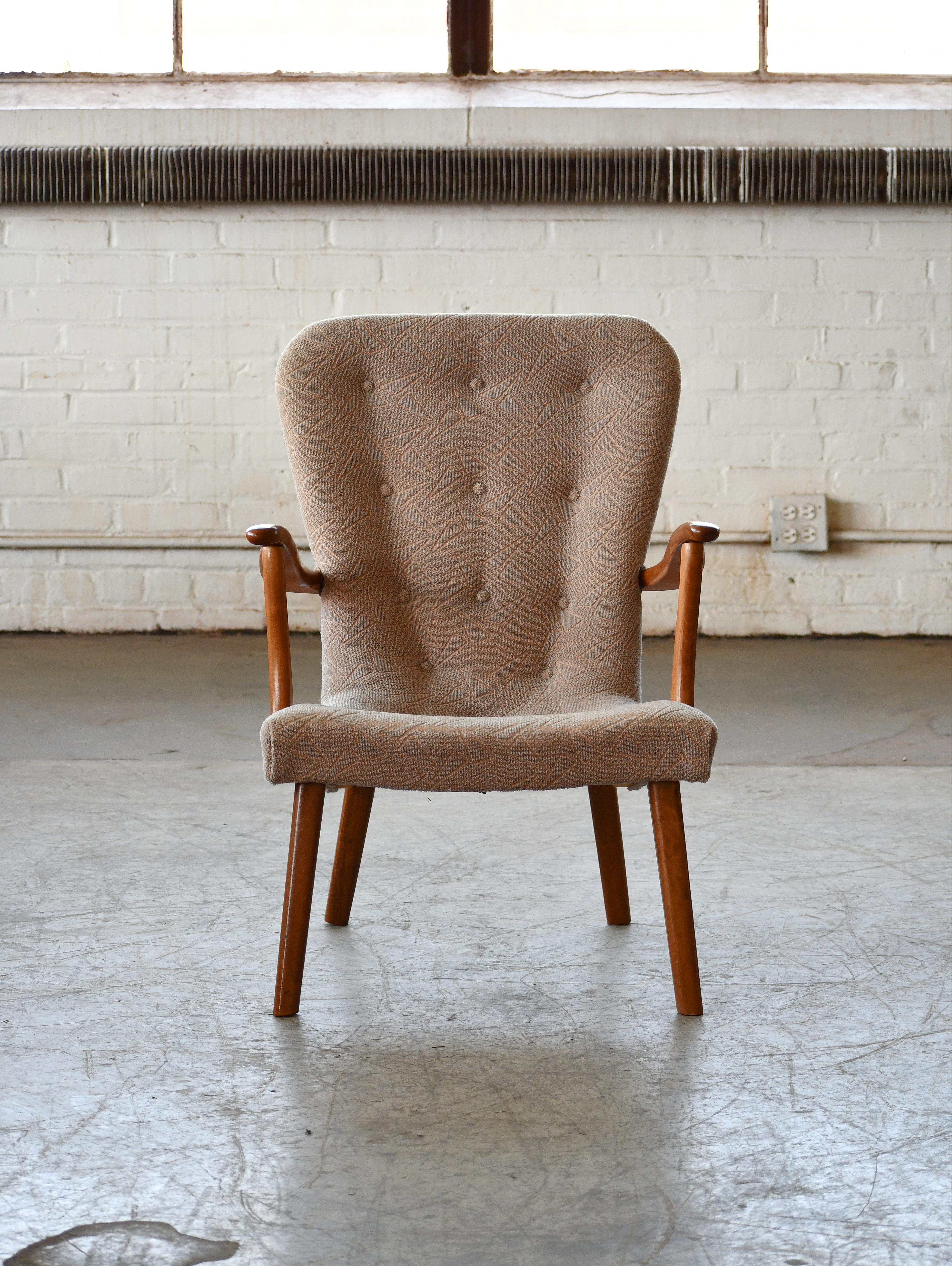 Charming lounge chair made in Denmark from stained and varnished beech wood. The design bears resemblance to the famous Pragh chair  by Schubell and Madsen and also has a stance and silhouette similar to Phillip Arctander's famous clam chair. Made