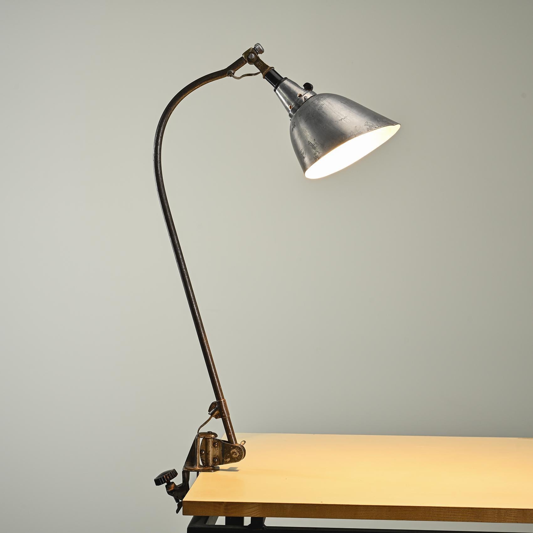 Clamp lamp from the 1930s, chosen by Walter Gropius to equip the Bauhaus building in Dessau in 1926.

This adjustable clamp lamp, known as model Typ 113 Peitsche, has a bent arm housing an aluminum sheet diffuser and a Bakelite switch.

Marked