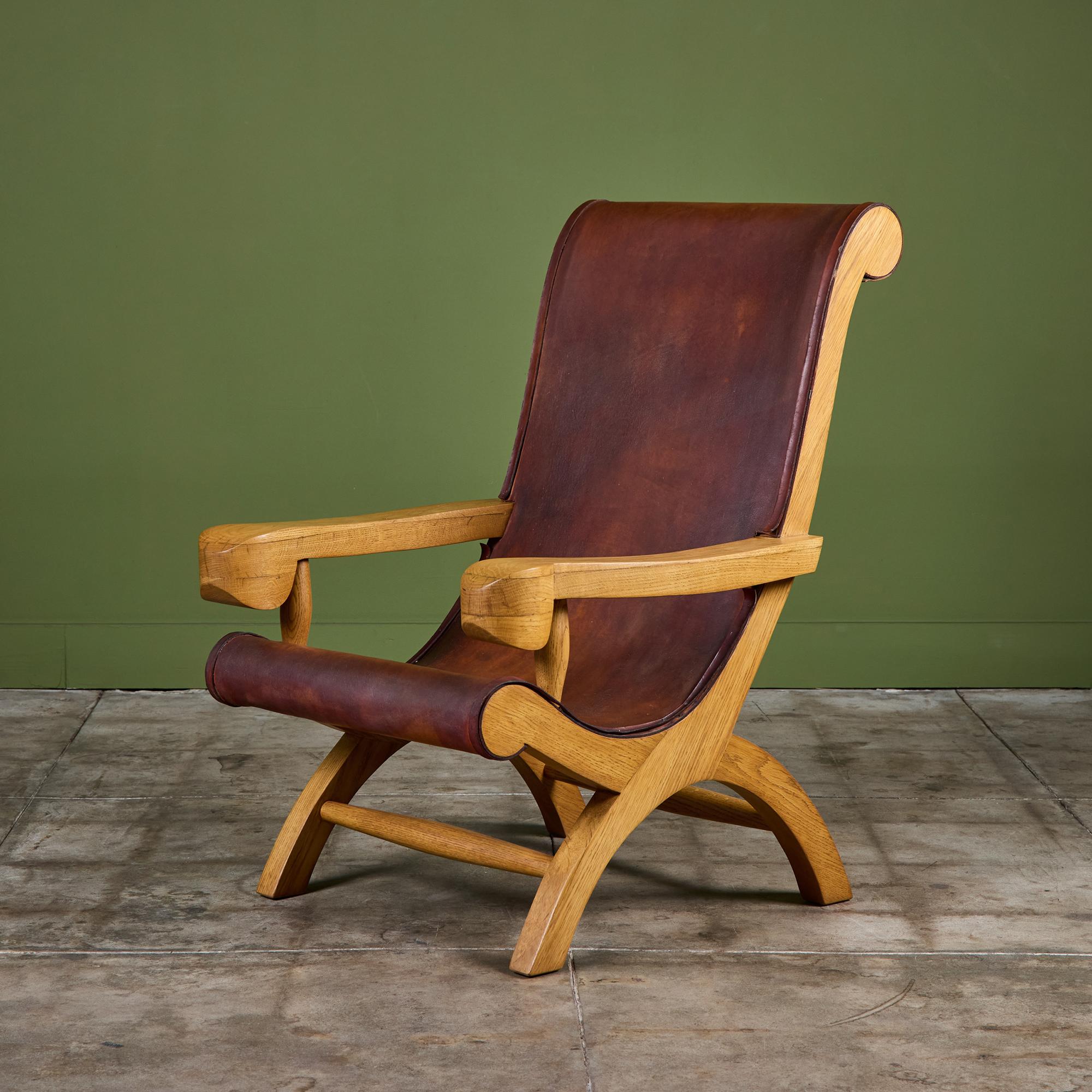Clara Porset 'Butaque' lounge chair c.1940s, Mexico. The lounge chair features a curvaceous solid cypress wood frame with the original brown saddle leather sling seat. The leather is wrapped around the frame and attached with patinated steel pins. 