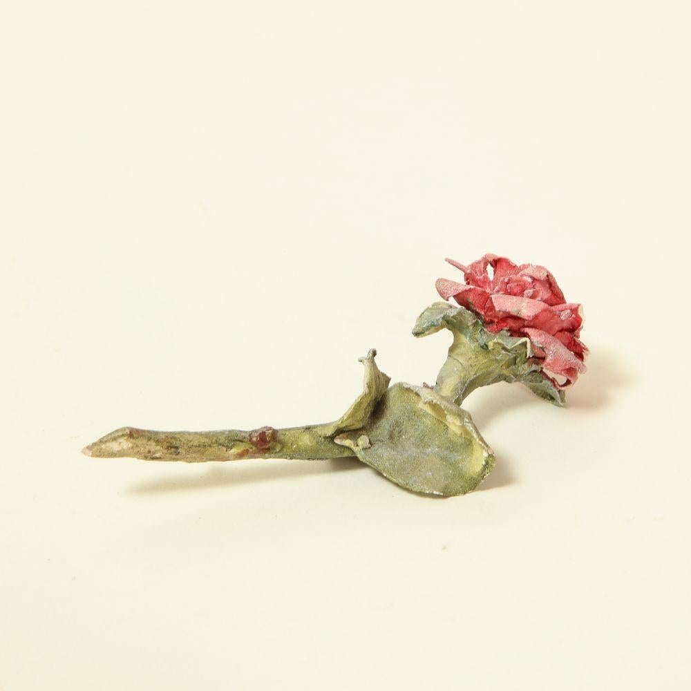 Modeled and painted by hand by acclaimed ceramicist Clare Potter.

The flower blossom formed of nicely detailed rose petals in a pink hue, the stem of sage green with naturalistic leaves and blunt knobs of thorns.