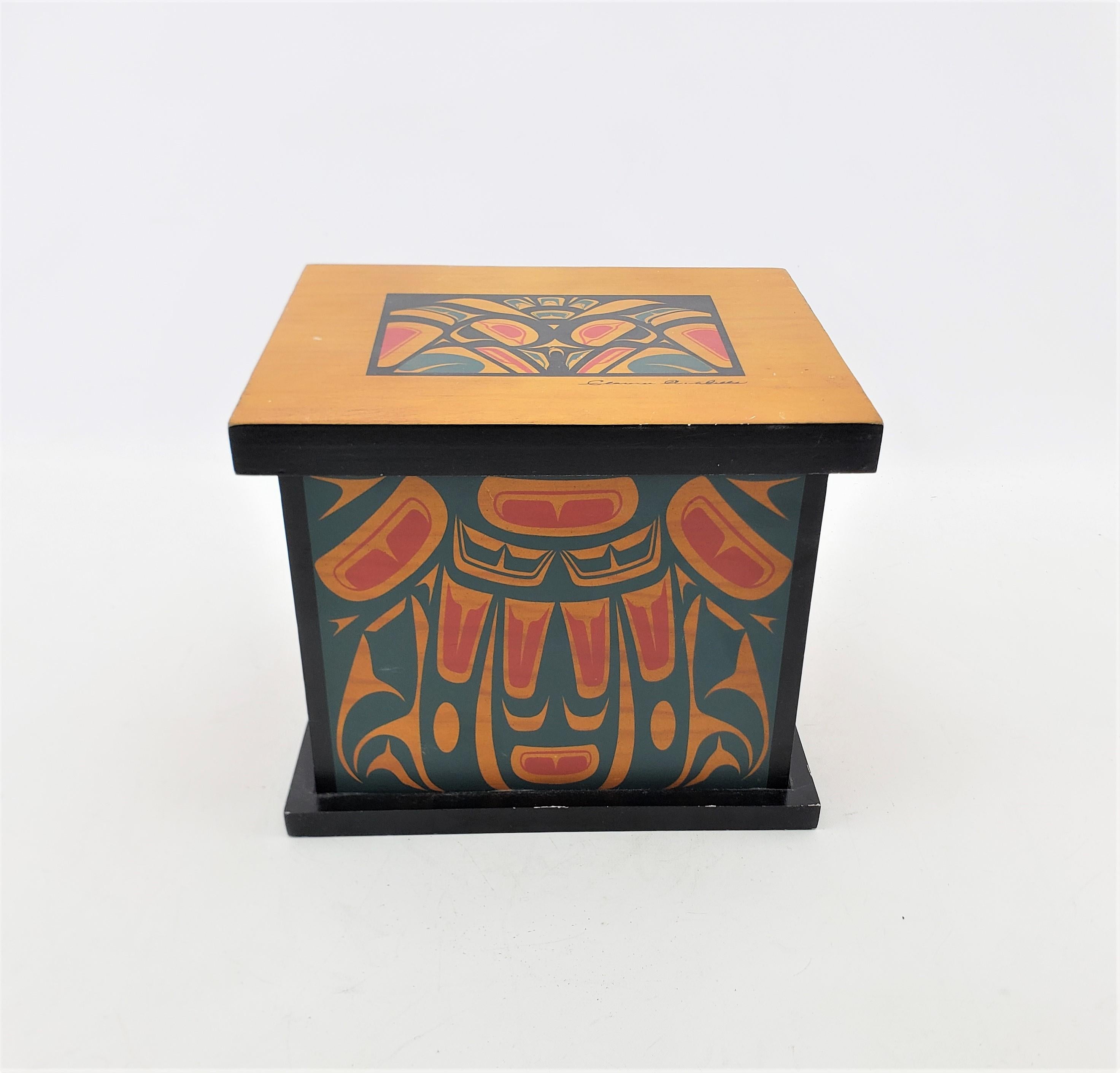 This decorative wooden box was designed by Clarence Wells of Canada and dates to approximately 1970 and done in the West Coast Haida style. The box is has silkscreened decoration on all four sides in muted tones of blue, and red with black accents.