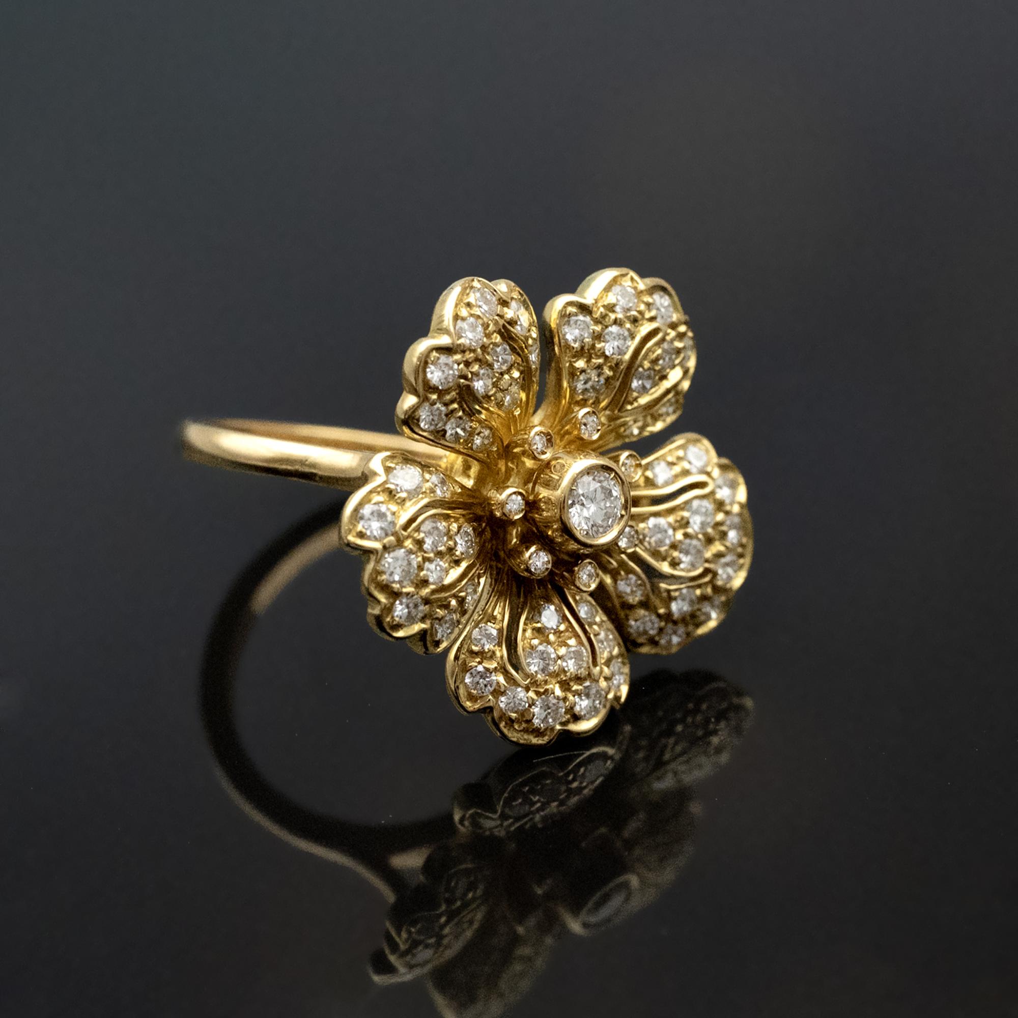 Cette bague en or jaune 18 carats est conçue comme une fleur stylisée composée de pétales de forme individuelle sertis de diamants blancs. Chaque pétale a une forme légèrement surélevée et séparée, créant un arrangement structuré qui permet aux