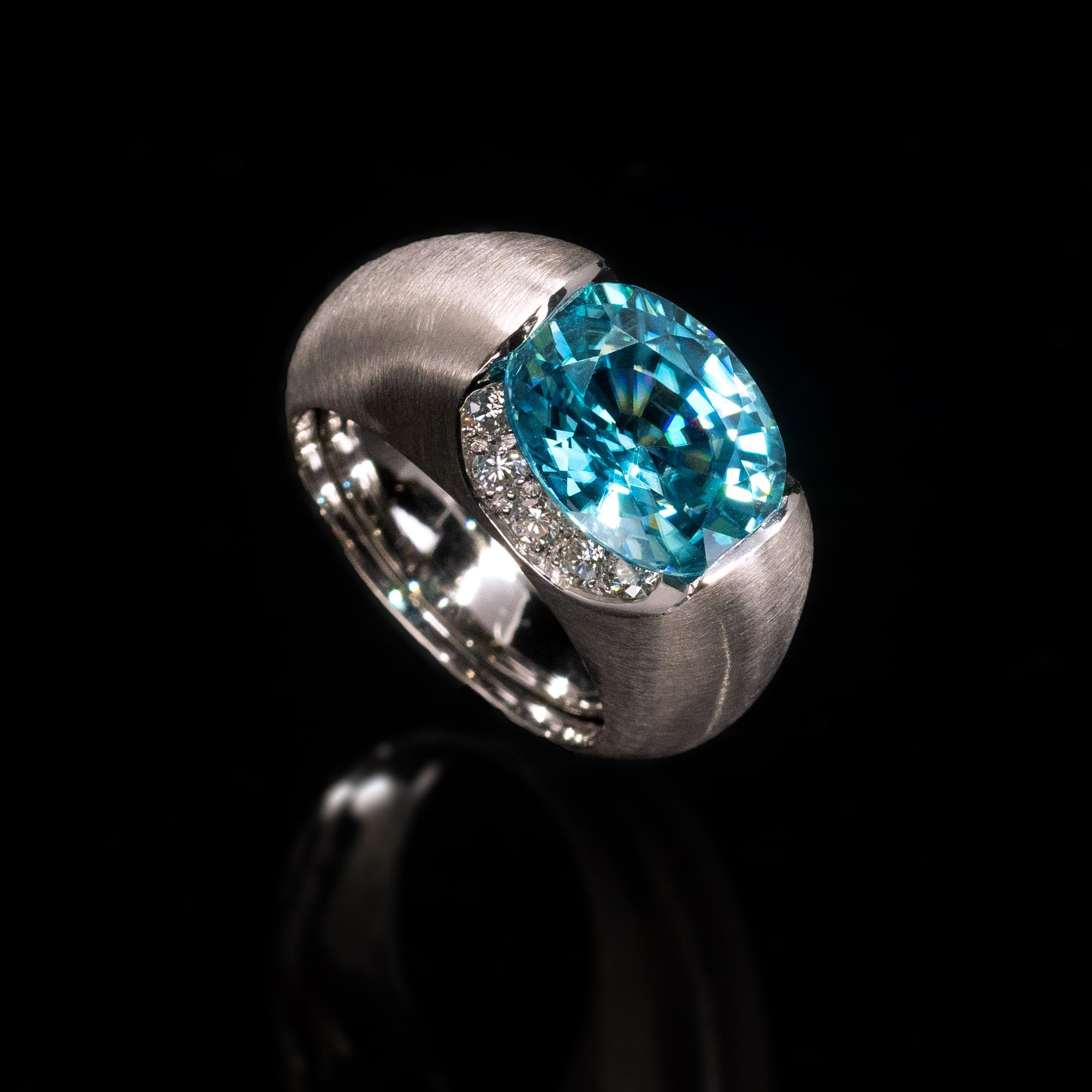 Stunning modern cocktail ring showcasing a vibrant blue zircon , a natural gemstone that shine and sparkle is often compared to diamond.  The design is modern and powerful:  perfect proportions and generous lines of the 18 Karat white gold band with