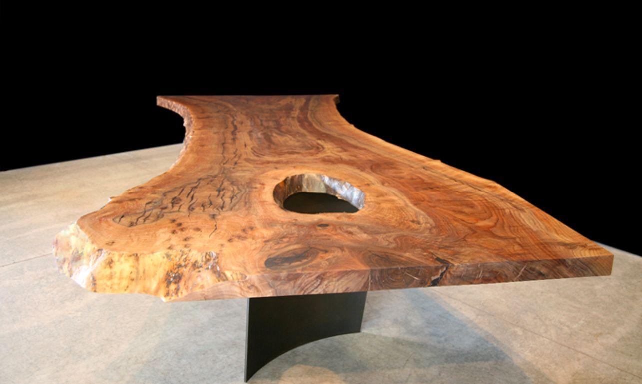 Claro walnut dining table with curved blackened steel legs.