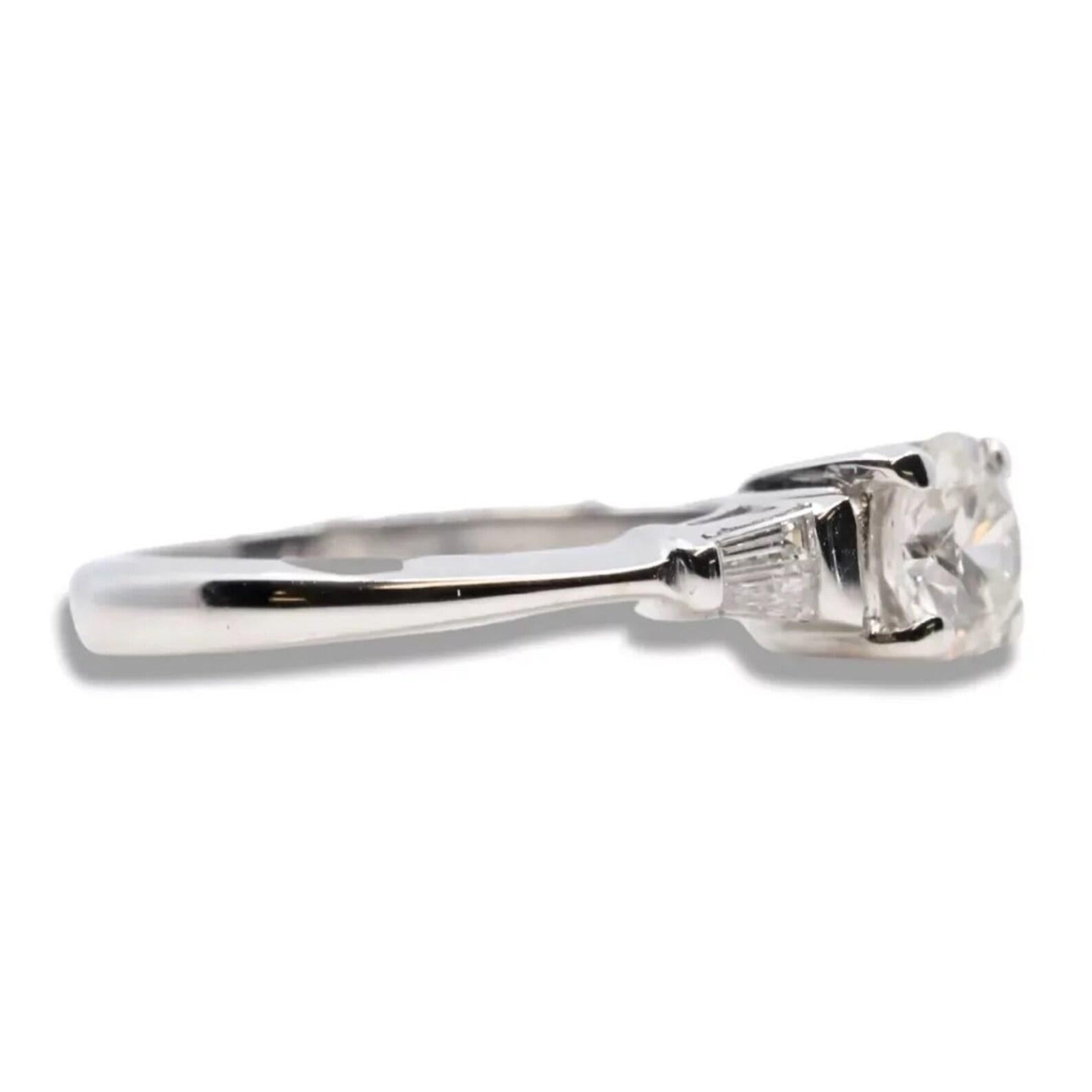 A contemporary ladies diamond engagement ring in 18 karat white gold. Centering this ring is a 0.52 carat G color SI2 clarity round brilliant cut diamond. Framing the center diamond are four accenting baguette cut diamonds. The four baguette cut