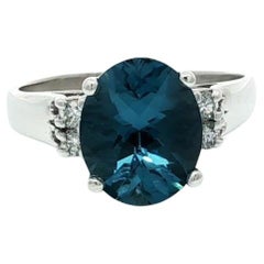 Anillo clásico de oro blanco de 14k con topacio azul londinense ovalado en damero y diamantes en los lados