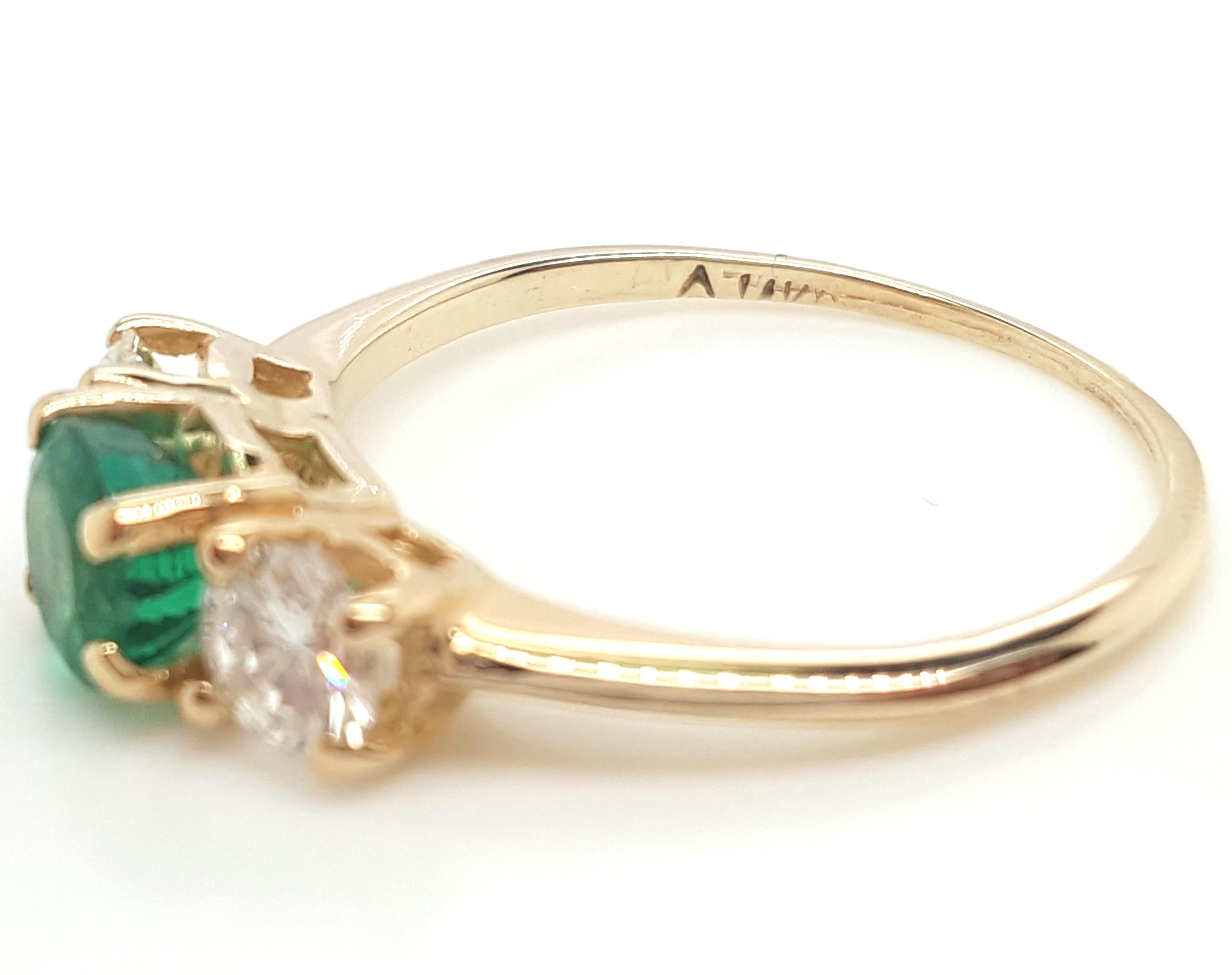 Classic 14K Yellow Gold Three-Stone Emerald and  Diamond Ring.   This classic three-stone ring is crafted in 14 karat yellow gold featuring a round emerald weighing approximately 0.56 carats,  set in a 14 karat yellow gold four prong setting,