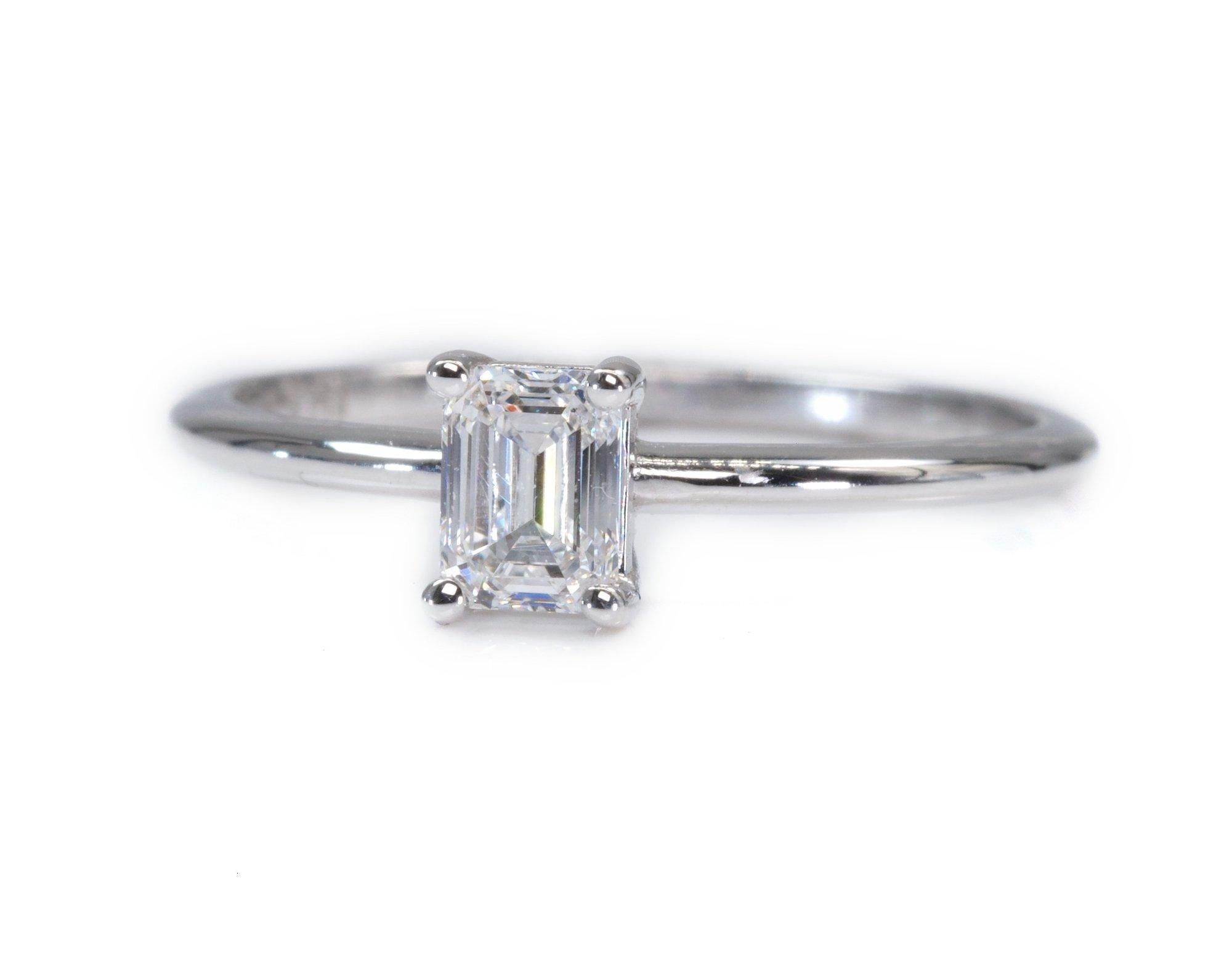 A beautiful classic solitaire ring with a dazzling 0.71 carat emerald cut natural diamond in D VS1, the whitest and highest possible colour of a diamond. The jewelry is made of 18K white gold with a high quality polish. The main stone is engraved