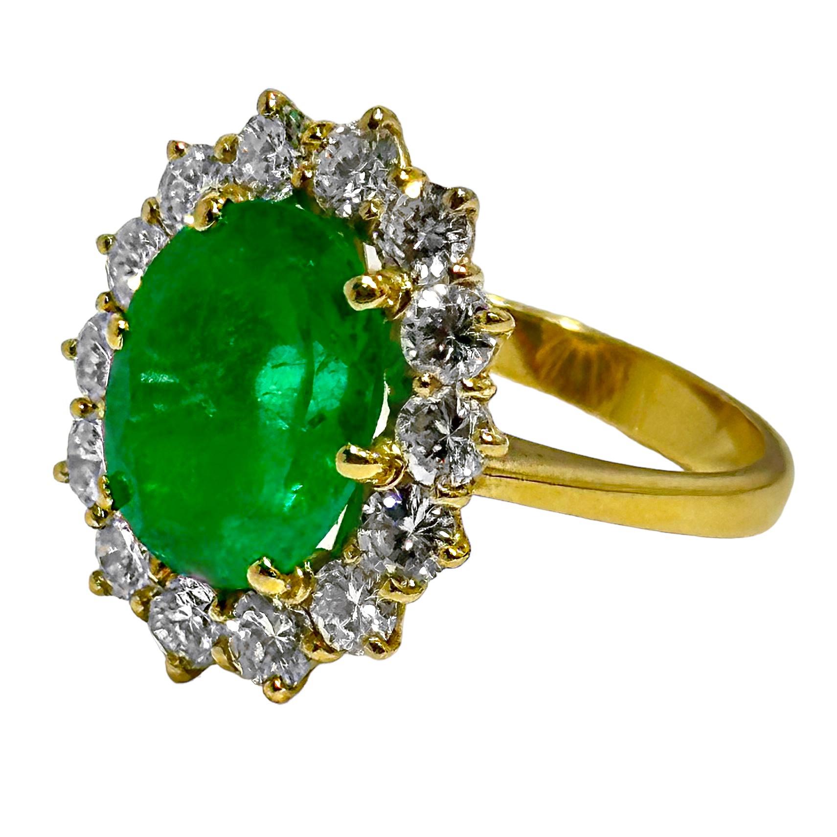 This classic style cocktail ring, fashioned in 18K yellow gold, features one oval shaped emerald surrounded by a halo of diamonds. The center stone weighs approximately 4.85ct and is a very pleasing green with a hint of blue in it. The 14 diamonds