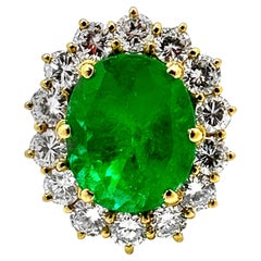Anello cocktail classico in oro giallo 18K con smeraldo ovale incorniciato da diamanti rotondi