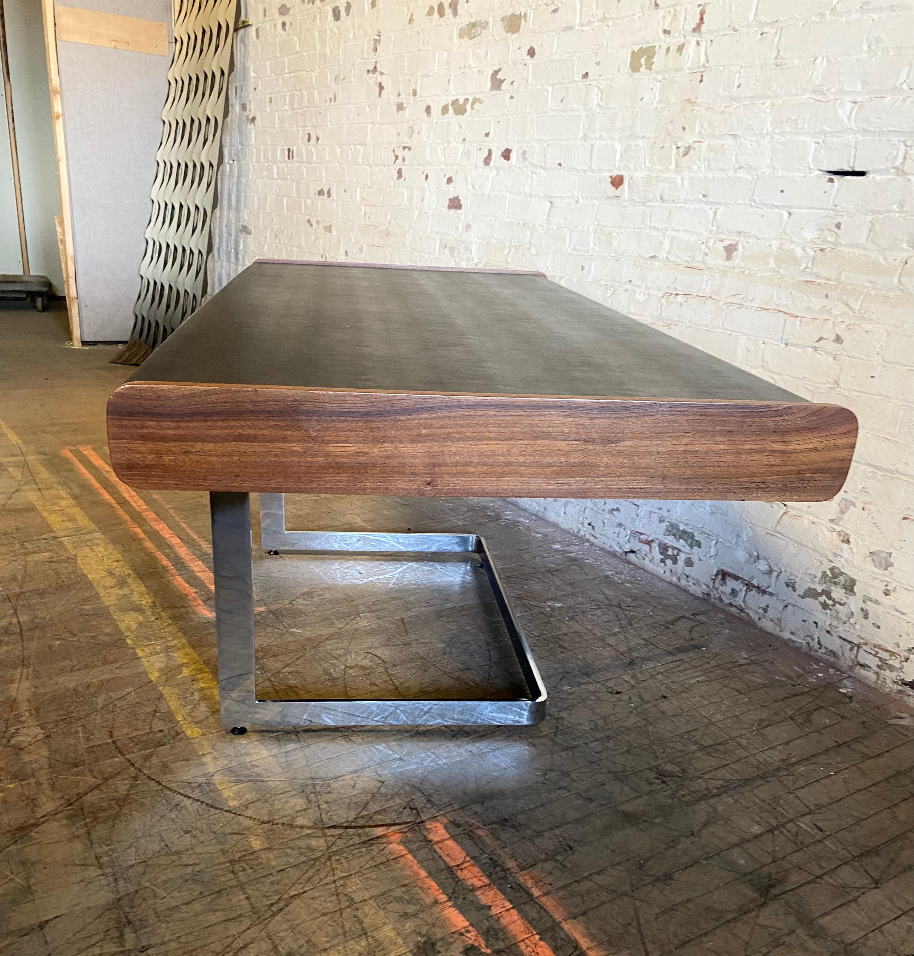 Stunning rosewood desk by Ste. Marie & Laurent. Desk floats on top polished chrome base. Entire desktop is wrapped in a black leather,, Wood and leather in good vintage condition. Excellent scale. Made in Canada, Circa 1960s: Hannd delivery avail to