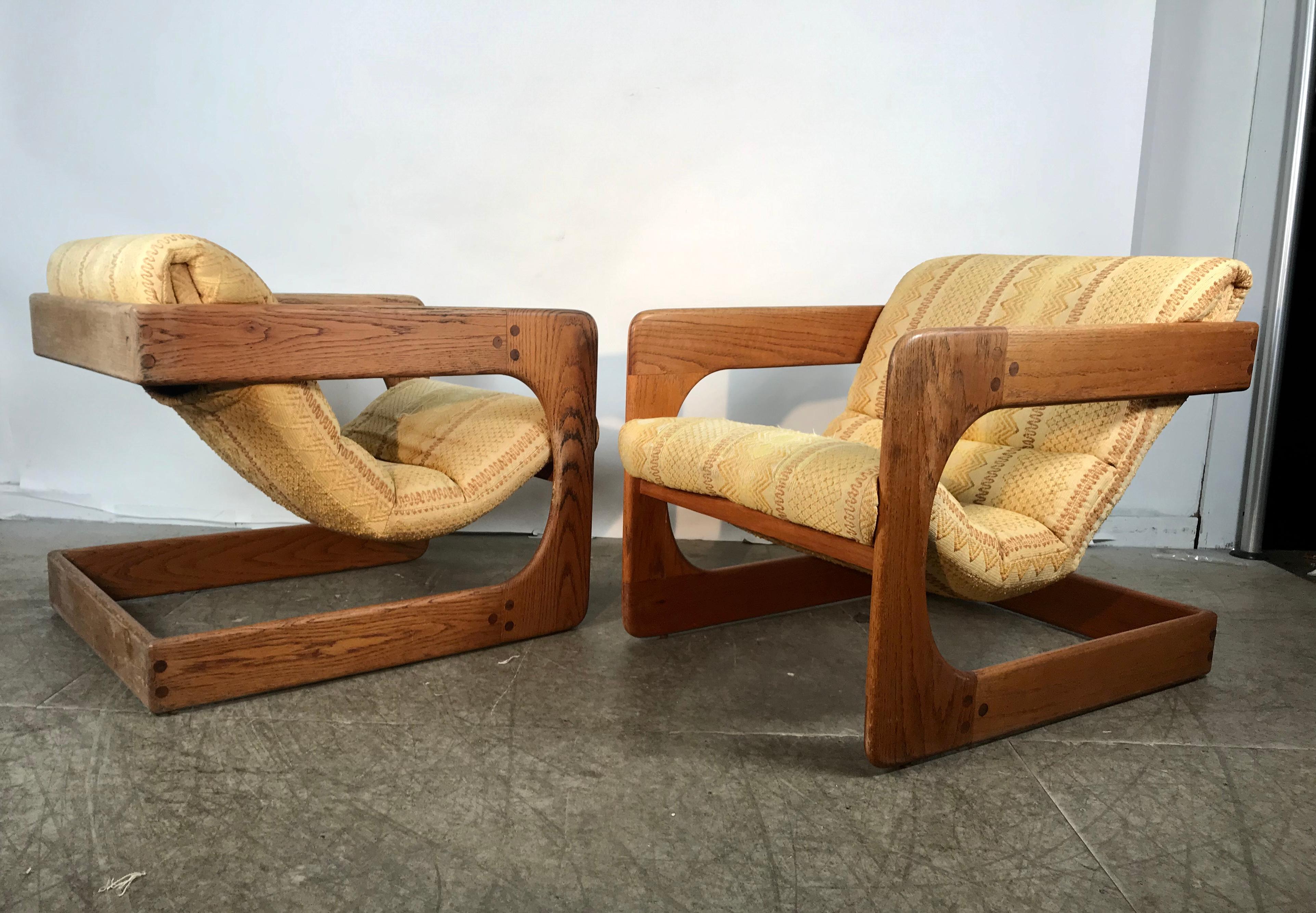 Classic pair of 1970s Cantilieved lounge chairs by Lou Hodges, California Design Group,, In original condition, Retain original pale yellow upholstery .age appropriate wear, minor tears, solid oakwood frames also original condition, bumps and