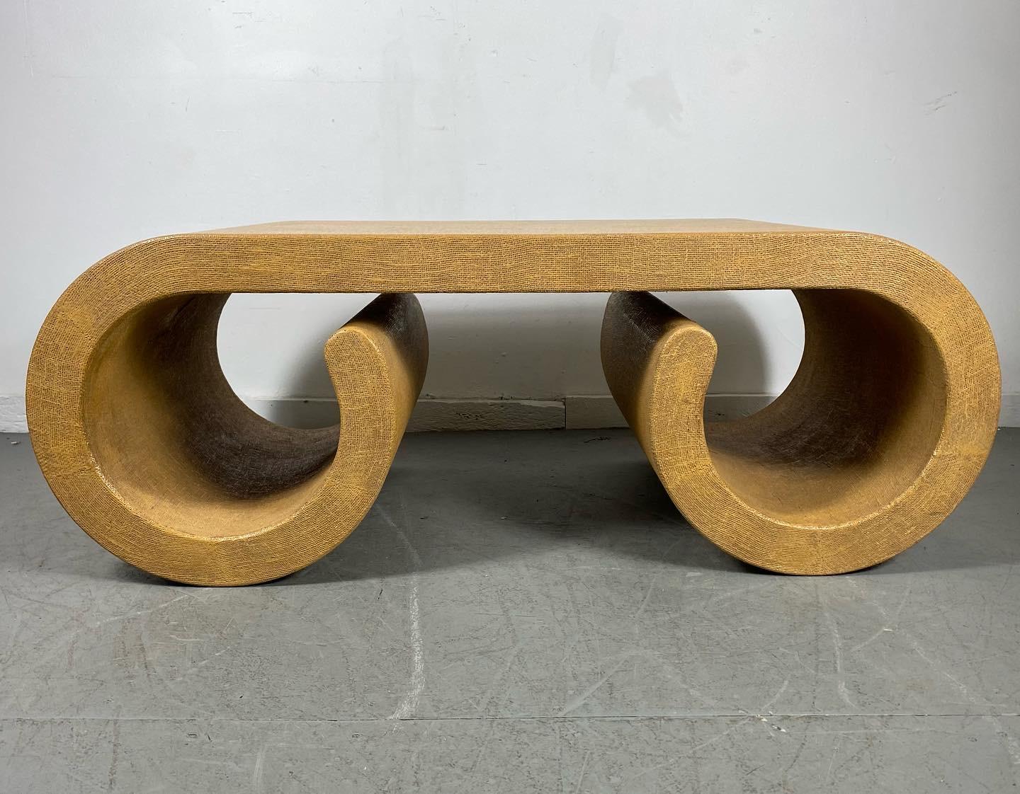 A large impressive scrolled coffee table from the 1970's in the style of Karl Springer. Extremely heavy and well made, it features oatmeal grass cloth finish..Beautiful piece of art ,sculpture as well as functional..Hand delivery avail to New York