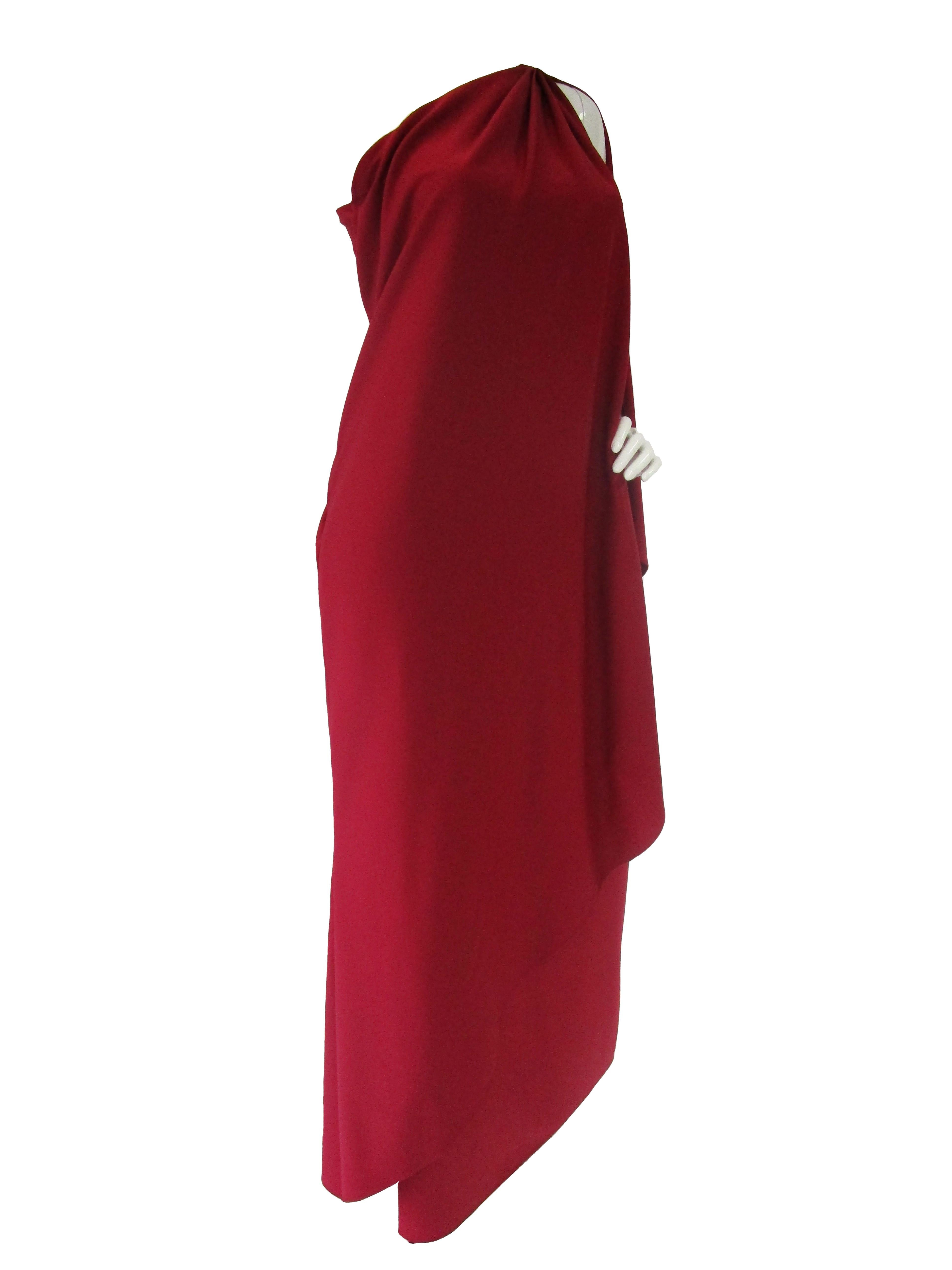 This elegant, ruby red, draped, Halston gown is “Classic Halston”.  With a sleeveless and ethereal bodice it is perfect for wear year-round. With a loose silhouette and a shoulder reveal, this is sure to be a showstopper. This gown is made by the