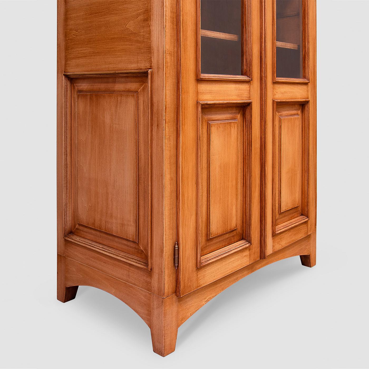 Dieses Bücherregal ist ein exquisites Beispiel für den klassischen Stil. Es besteht aus einer hohen Struktur, die vollständig von Hand aus Tulipwood gefertigt und mit ungiftigen, nachhaltigen Lacken in hellem Nussbaum gebeizt wurde. Die Türen mit