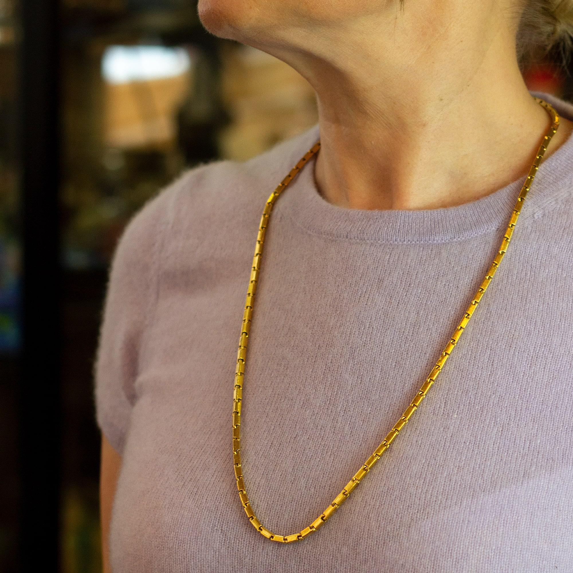 This substantial pure gold necklace likely originates from Thailand or a neighbouring country and is known as a 'Baht' necklace. The links are known as 'bar links' and are rectangular prisms connected to one another at their narrowest point. The