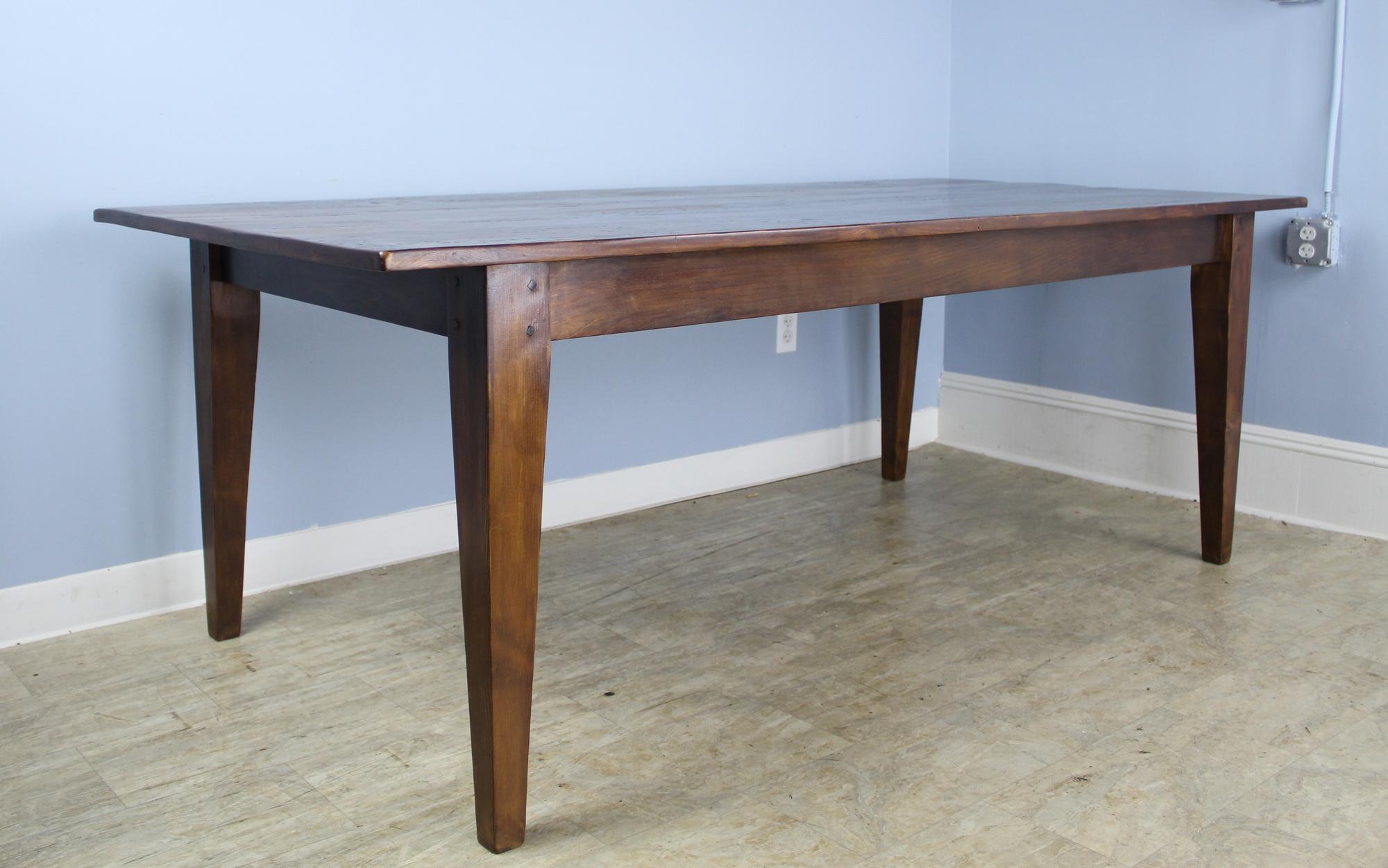 A generously proportioned, thick topped pine farm table in medium walnut 7' with some mild faux distress. With 68 inches between the legs, this table can easily fit eight with room for a Thanksgiving dinner as well! The apron height of 25 inches is