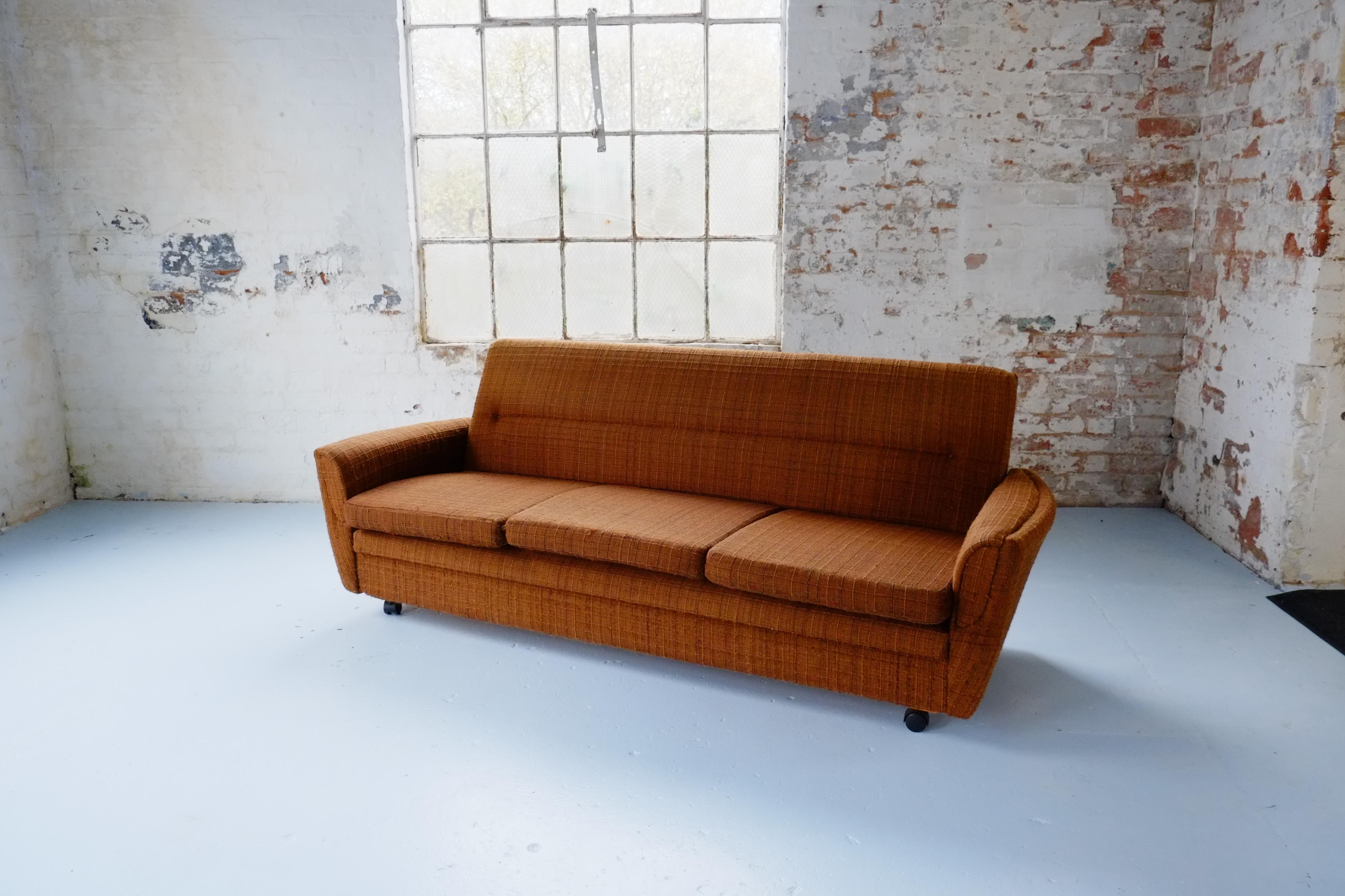 A rare find - an original 1970s brown fabric settee, that transforms into a small double bed for occasional guests. The sofa has lovely curved armrests and elegant proportions. The fabric is original, clean, and has a bobbly '70s signature texture