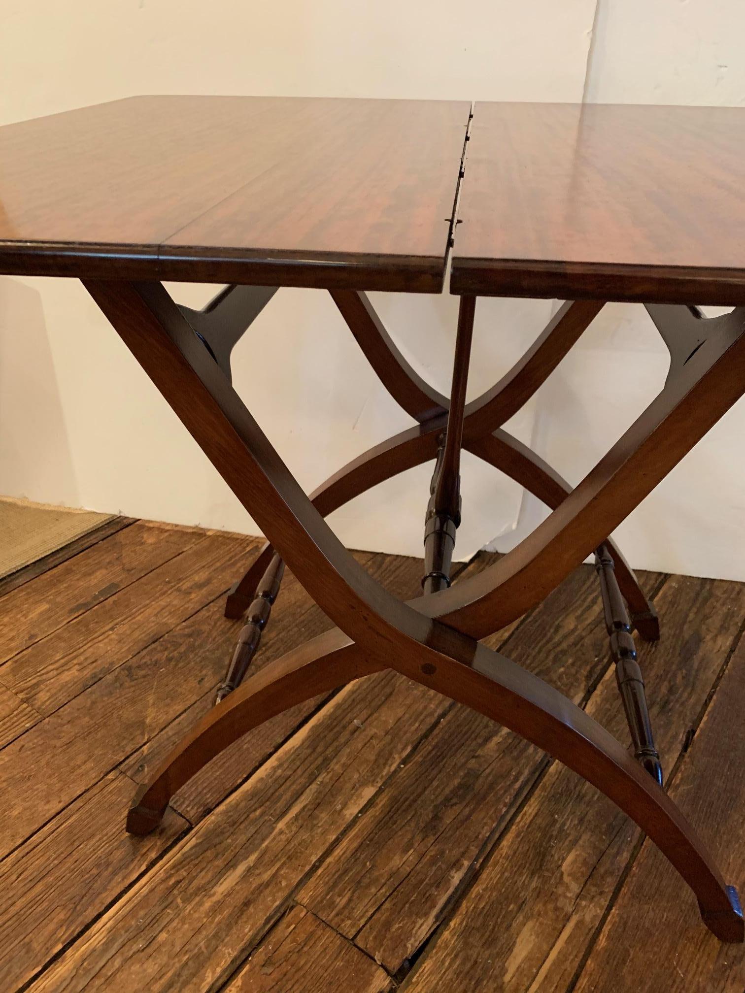 A nifty versatile beautifully crafted Campaign style mahogany table by Benjamin Ferber that opens to become a side table or small dining table having a bar underneath that clasps around the stretcher and locks in place. A super space saver, the